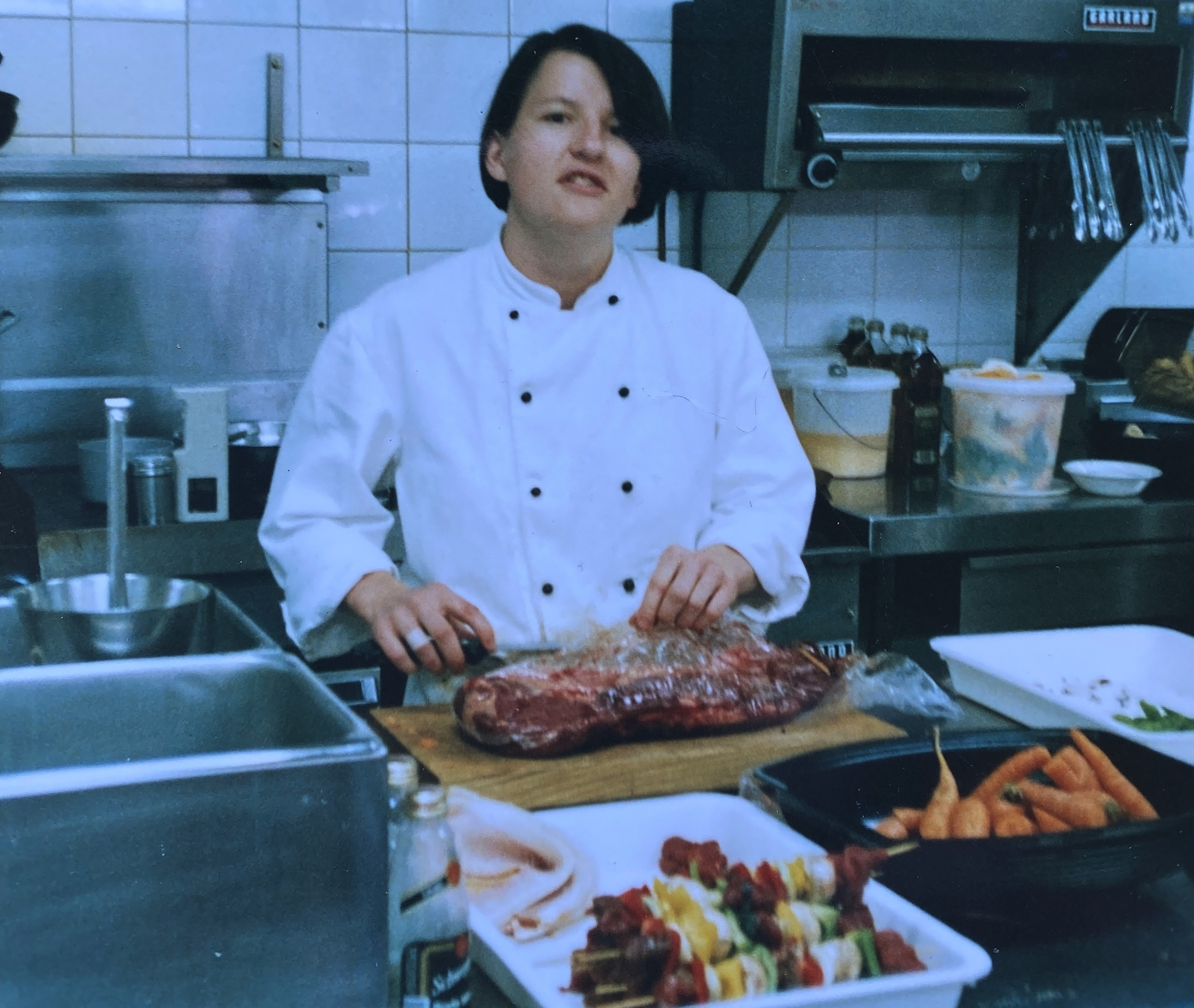 A chef holding a knife over a cut of meat.