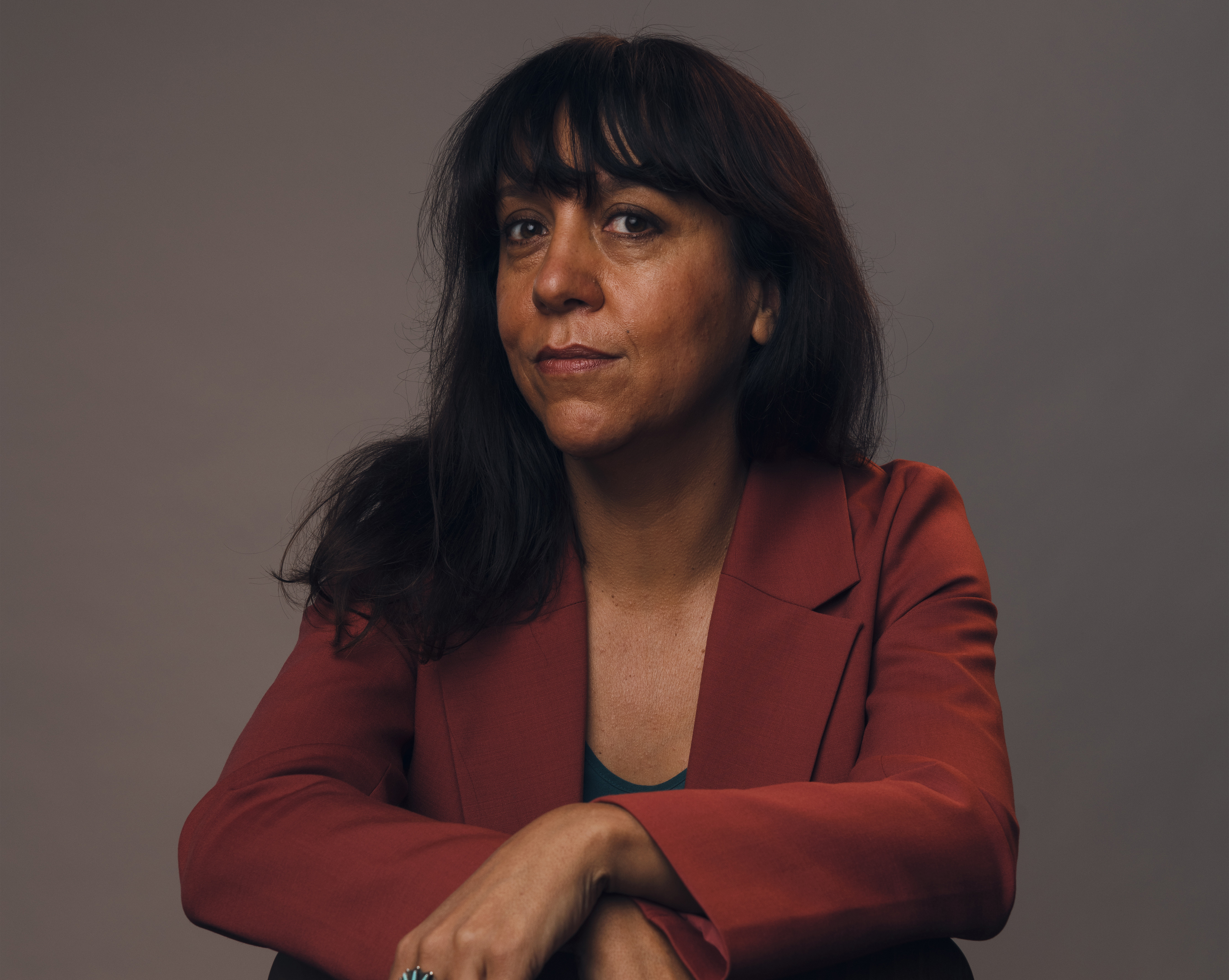 Portrait image of Rachel Perkins wearing an orange blazer.