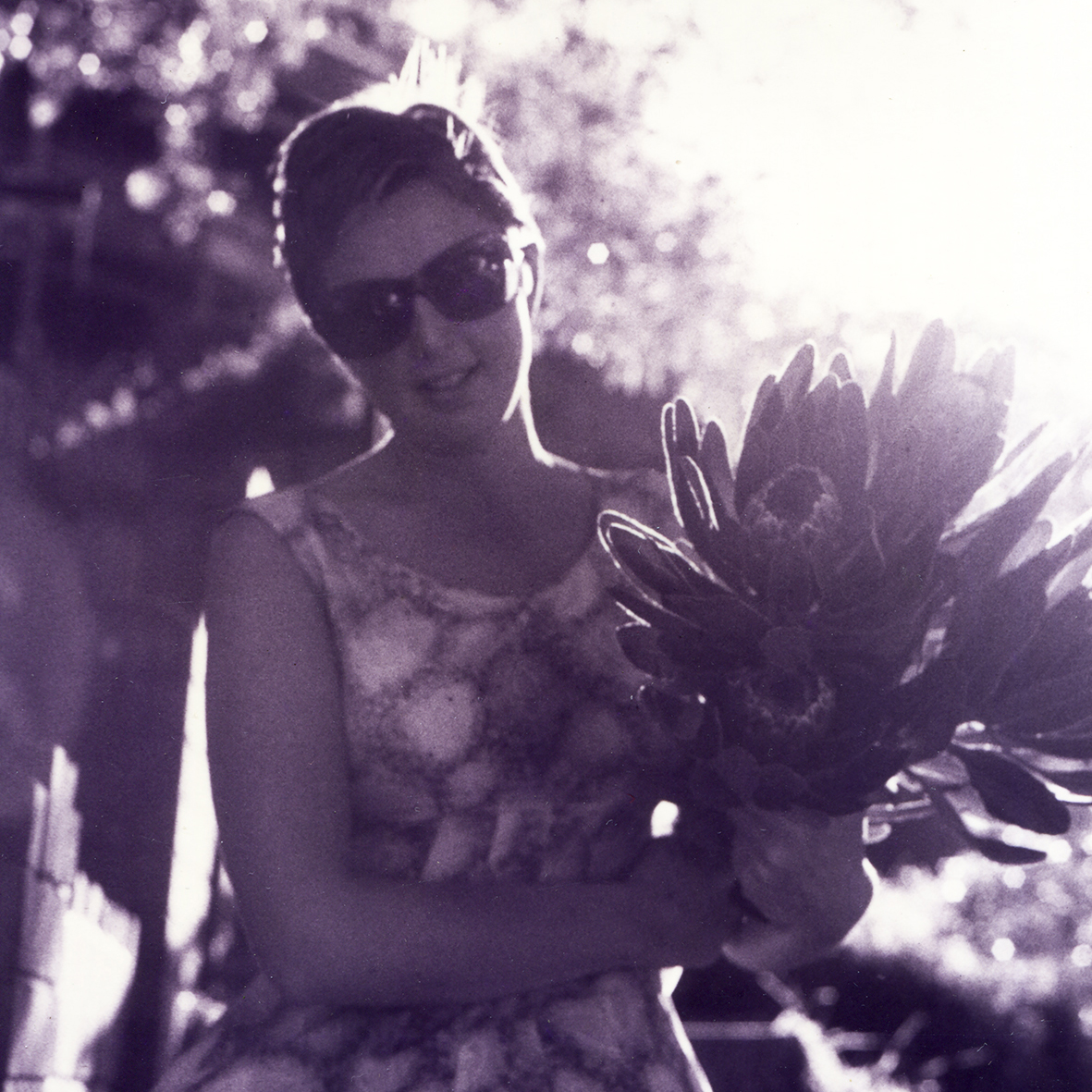 A woman with short hair holding a bouquet of flowers.