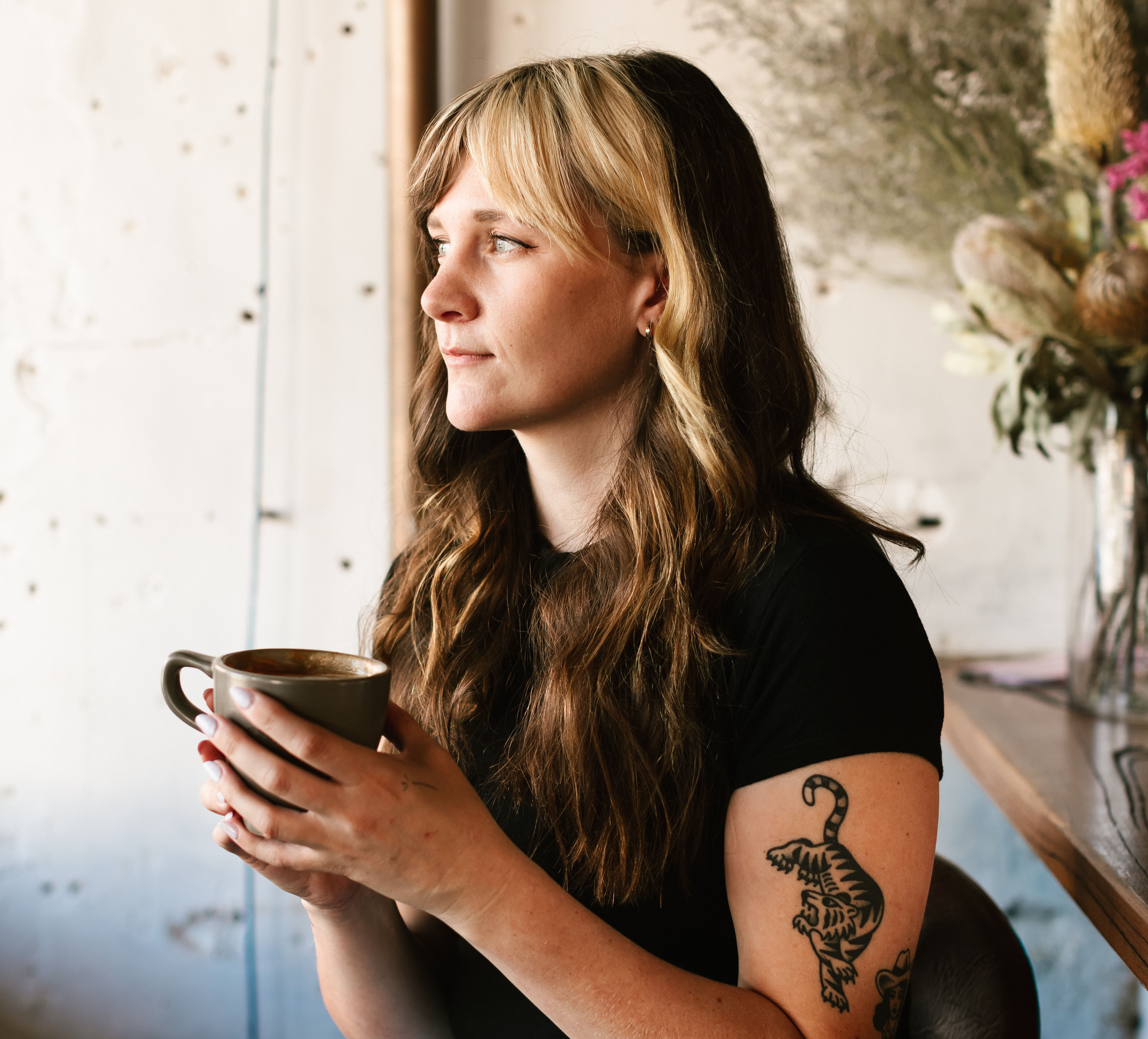 A young woman with a blonde fringe and holding a mug in her hand.