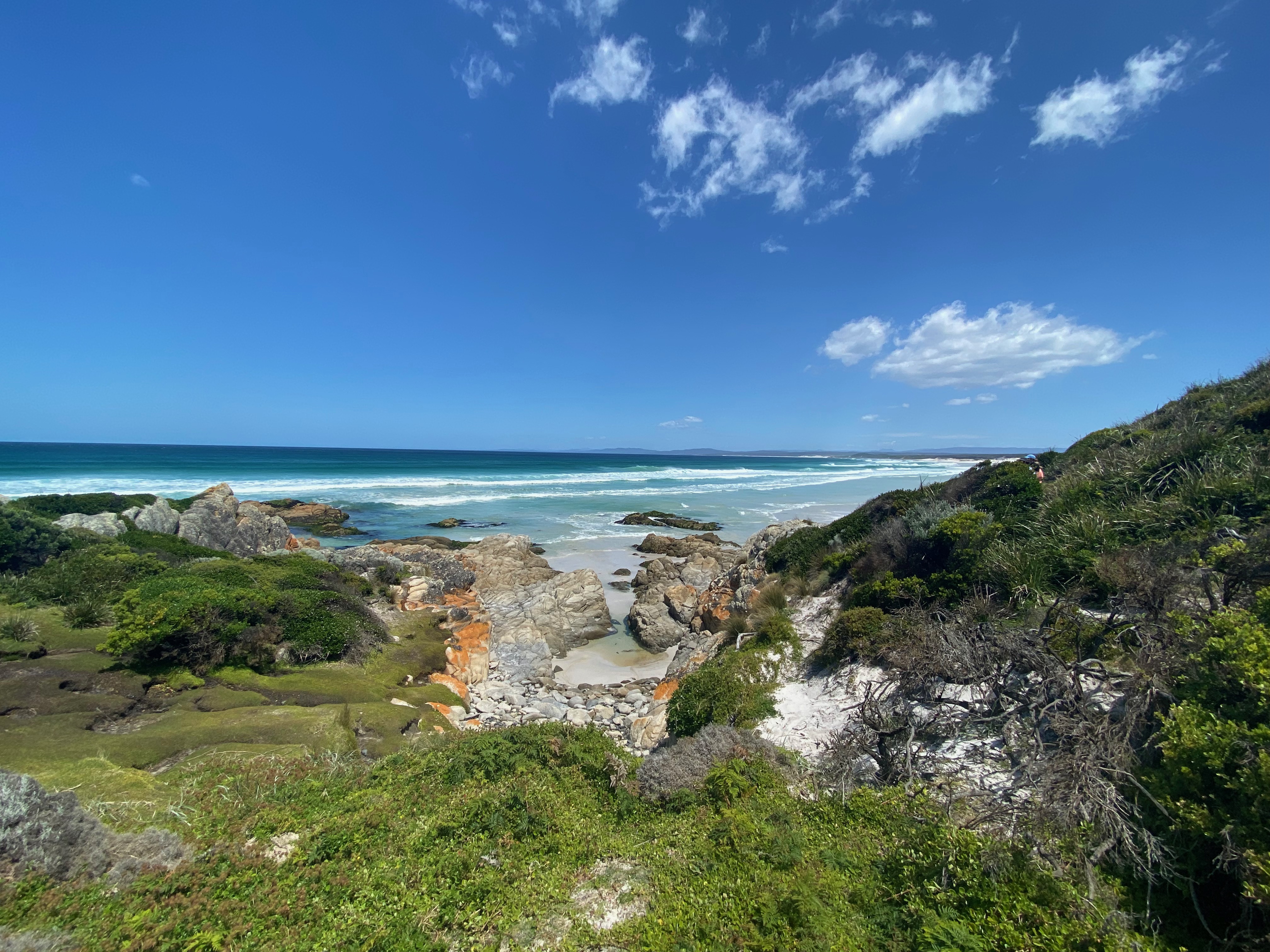 Landscape image of a beach with white sand and crystal blue water.