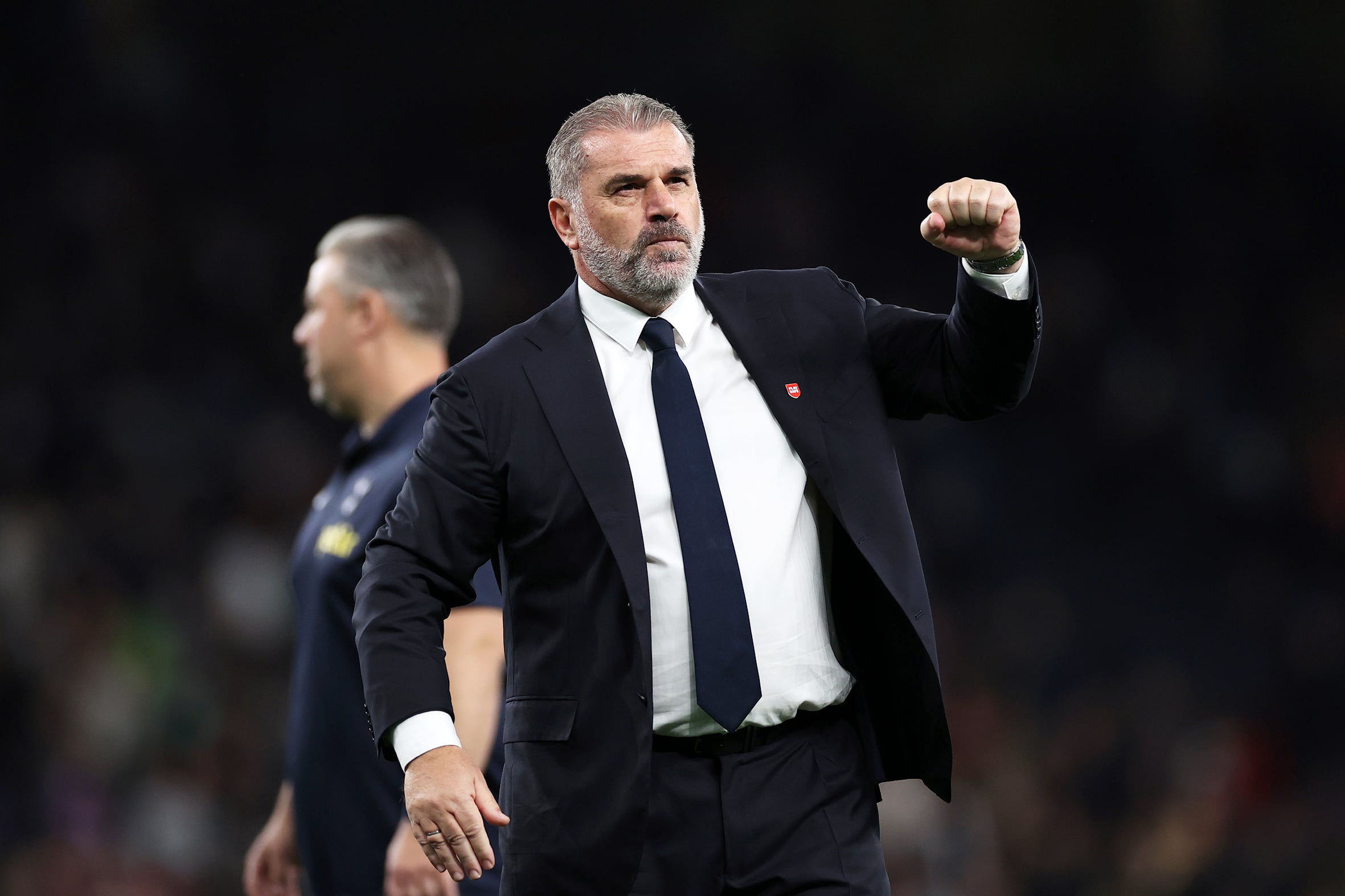 A middle-aged man dressed in a suit with his fist in the air.