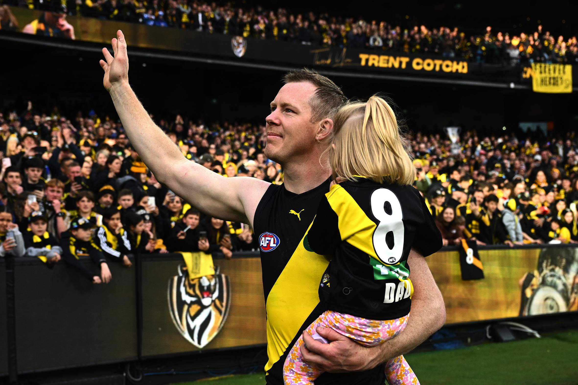 Jack Riewoldt holding his daughter as he waves to a crowd of Richmond supporters at the MCG.