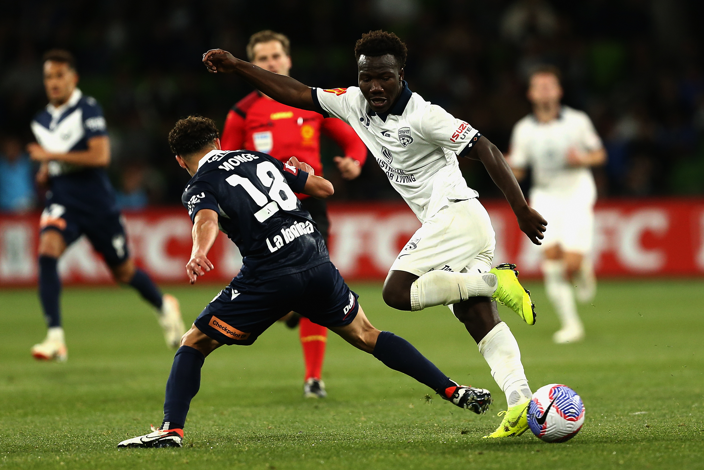 A soccer player dribbles around a defender.