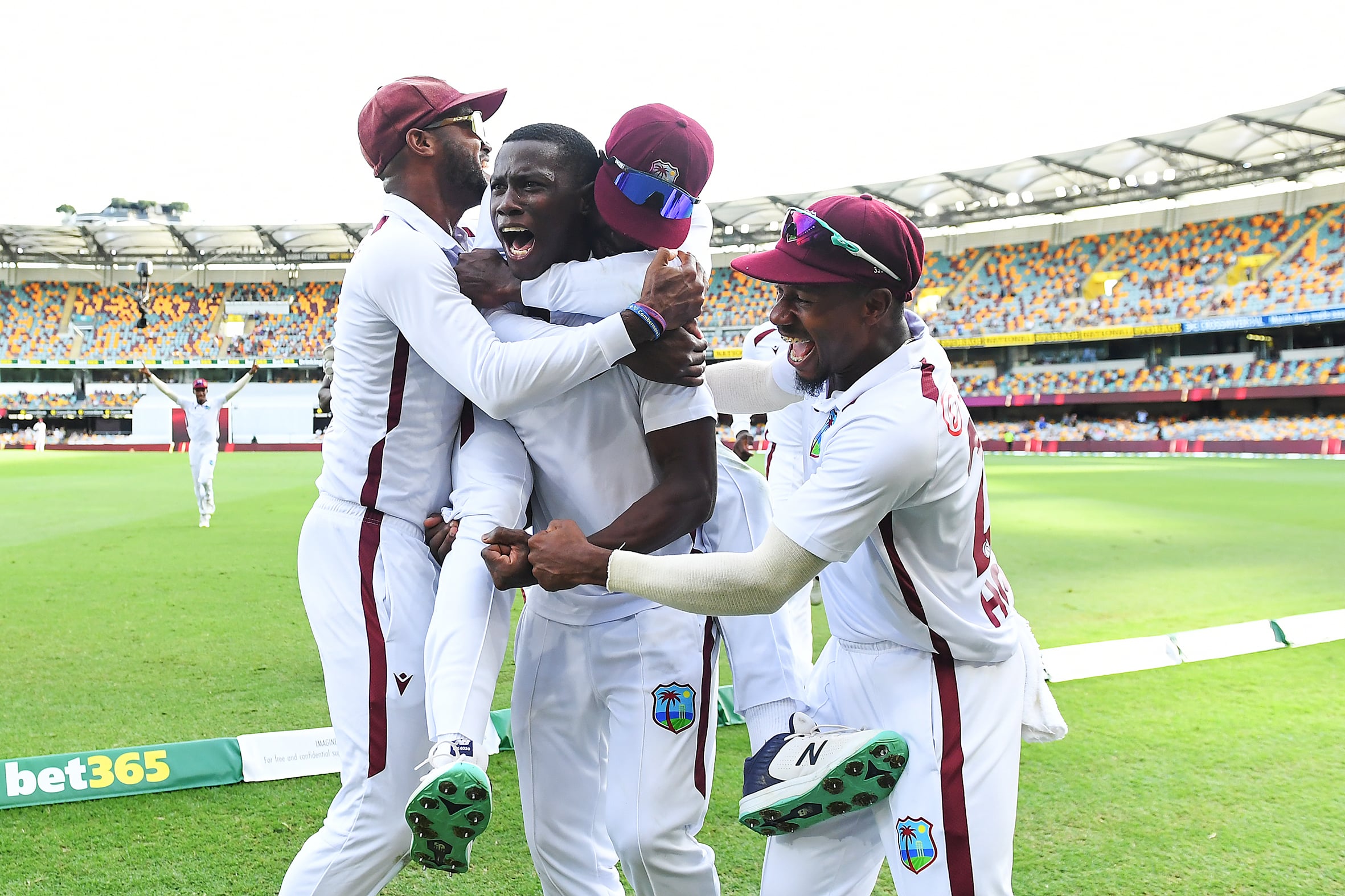 Cricketers jumping in celebration by the boundary line. 