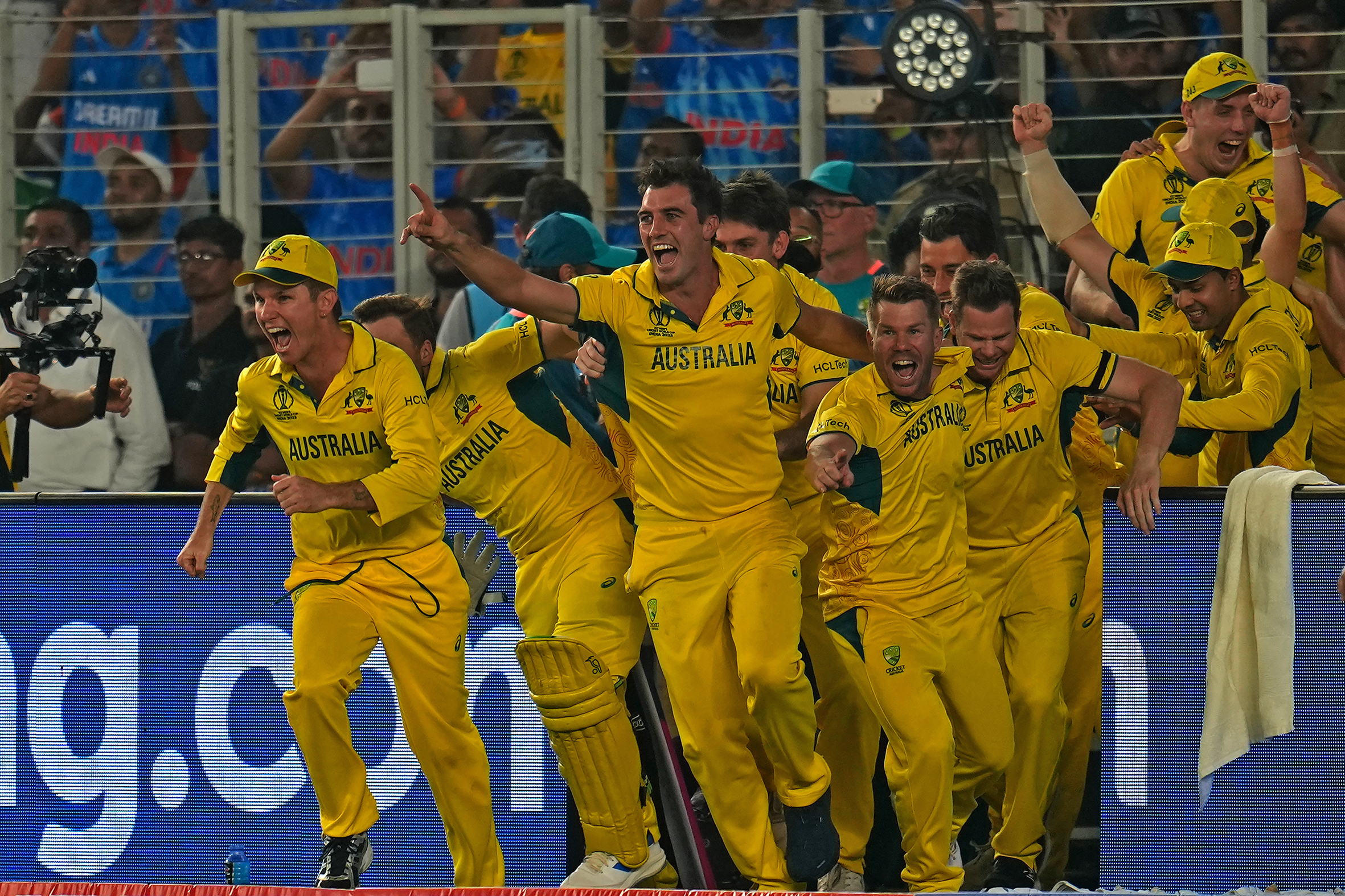 The Australian team, led by Pat Cummins, storm the field.