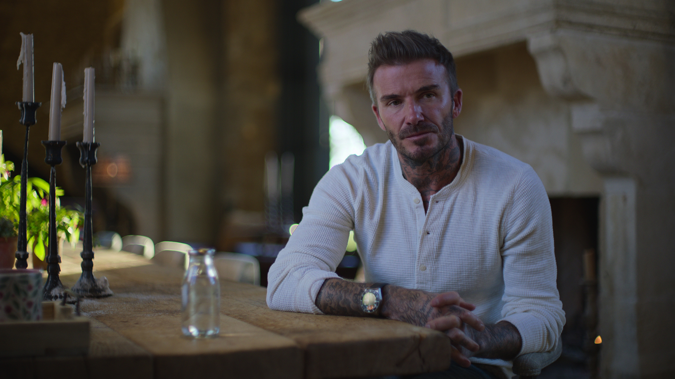 David Beckham sits at a dining table.