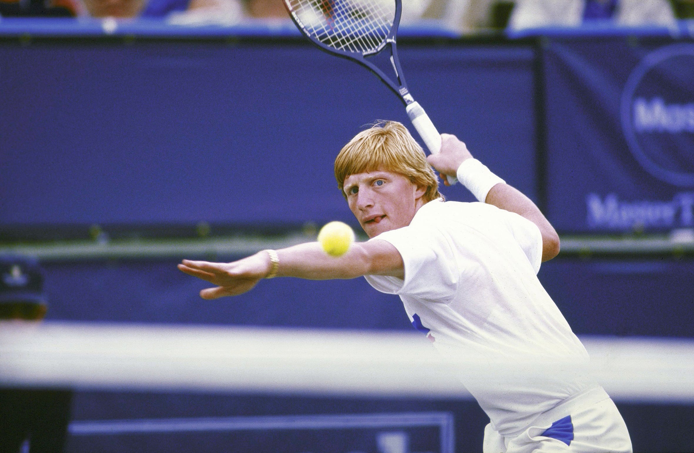 Boris Becker on court and eyeing a tennis ball, preparing for a forehand. 