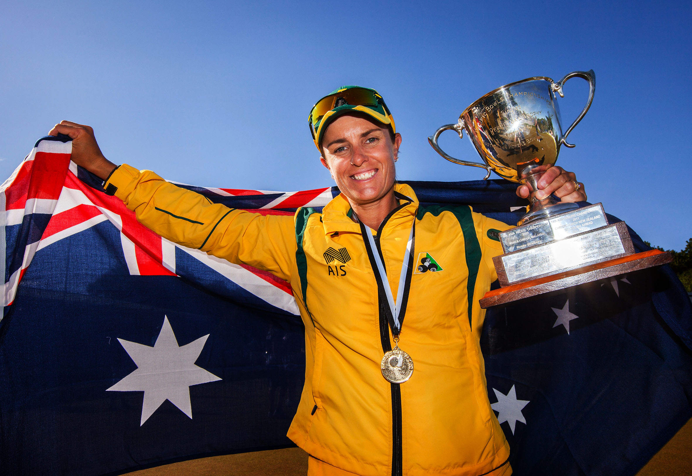 Lawn bowler Karen Murphy holds a trophy and the Australia flag