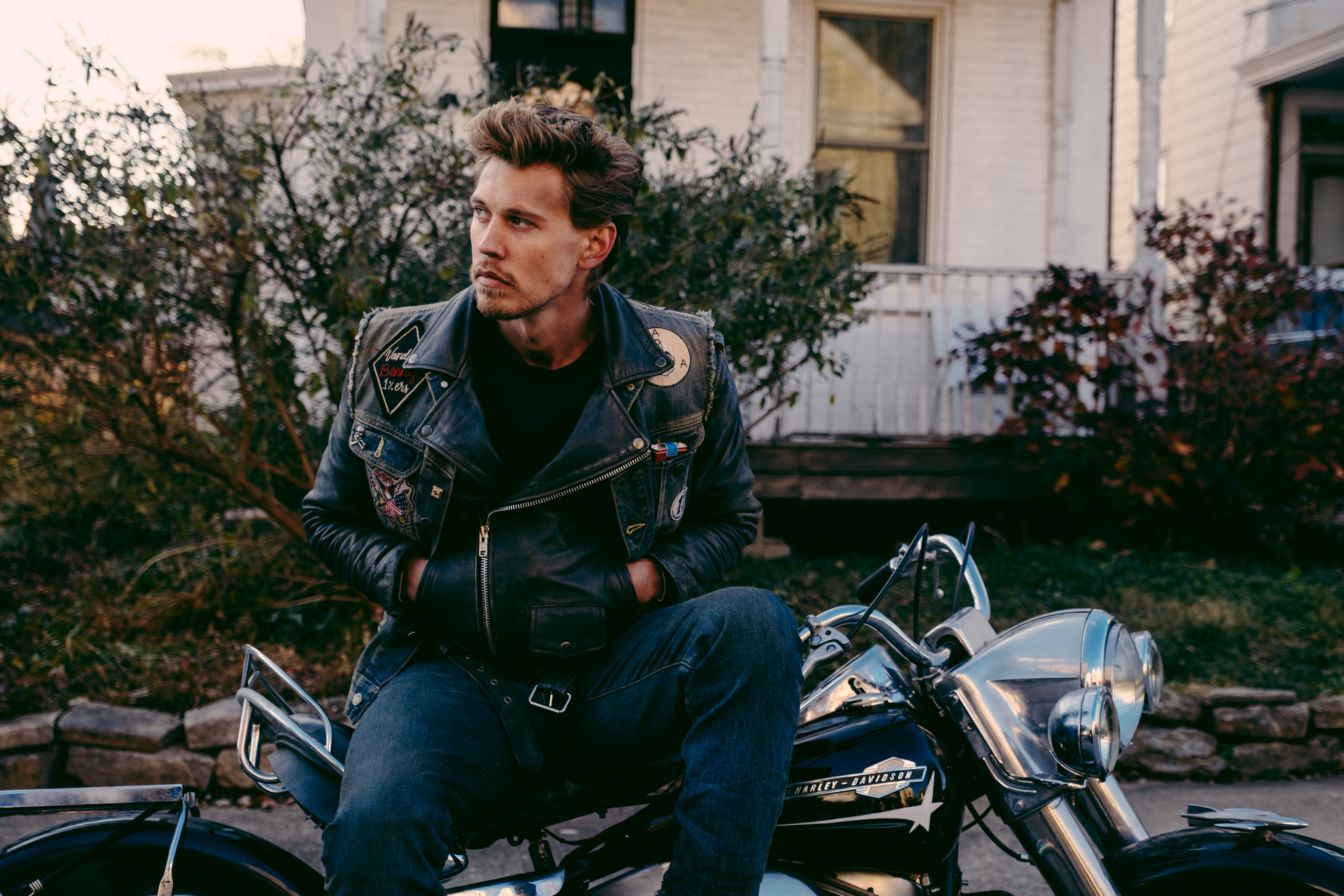 On the set of The Bikeriders, actor Austin Butler sits on his character's 1964 Harley-Davidson motorcycle.
