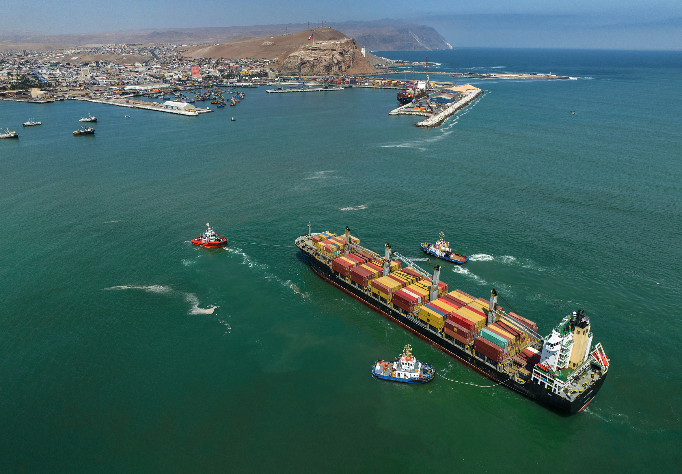 Tugboats guide a container ship into the Port of Arica in northern Chile. 