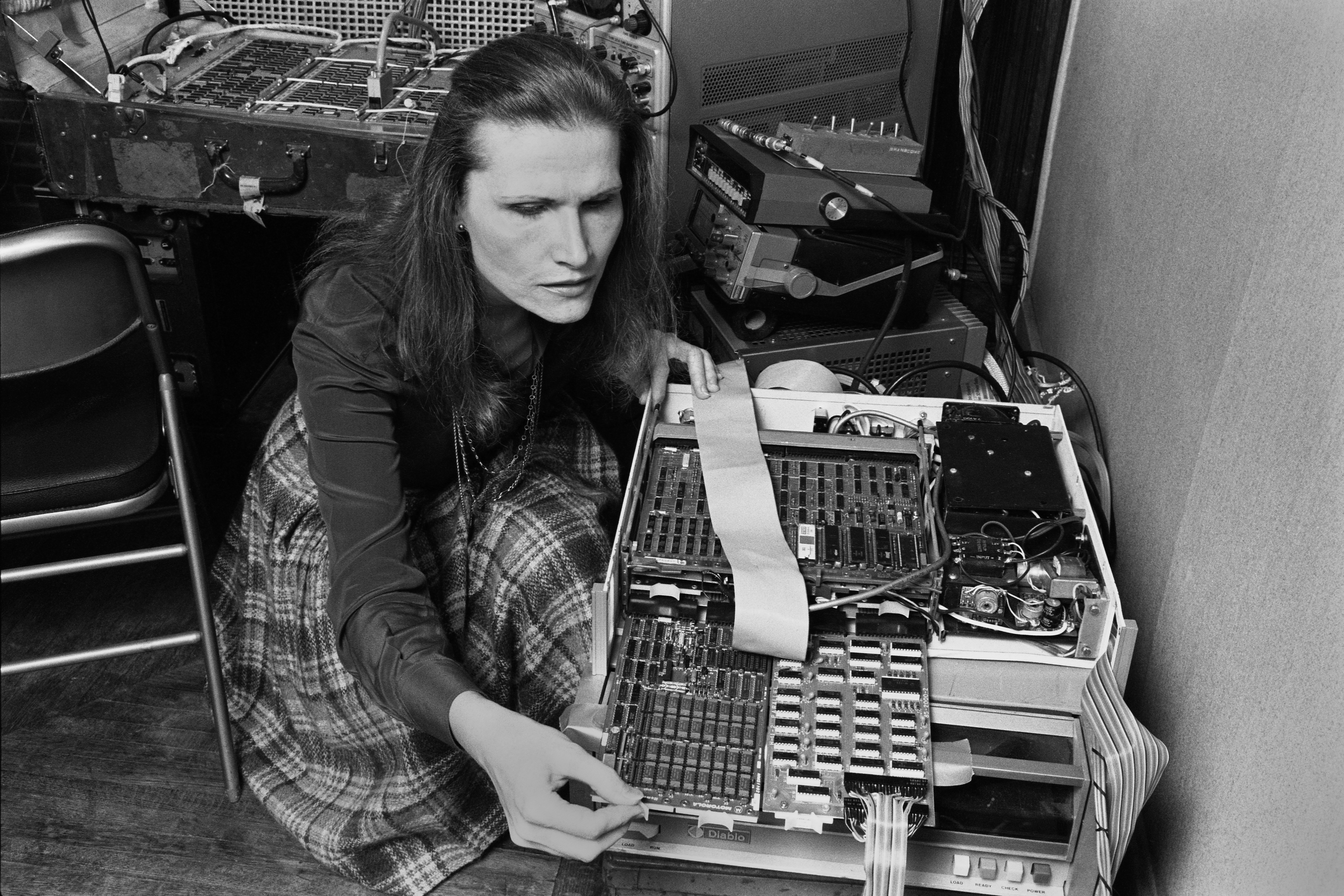 An electronic musician leans over their equipment.
