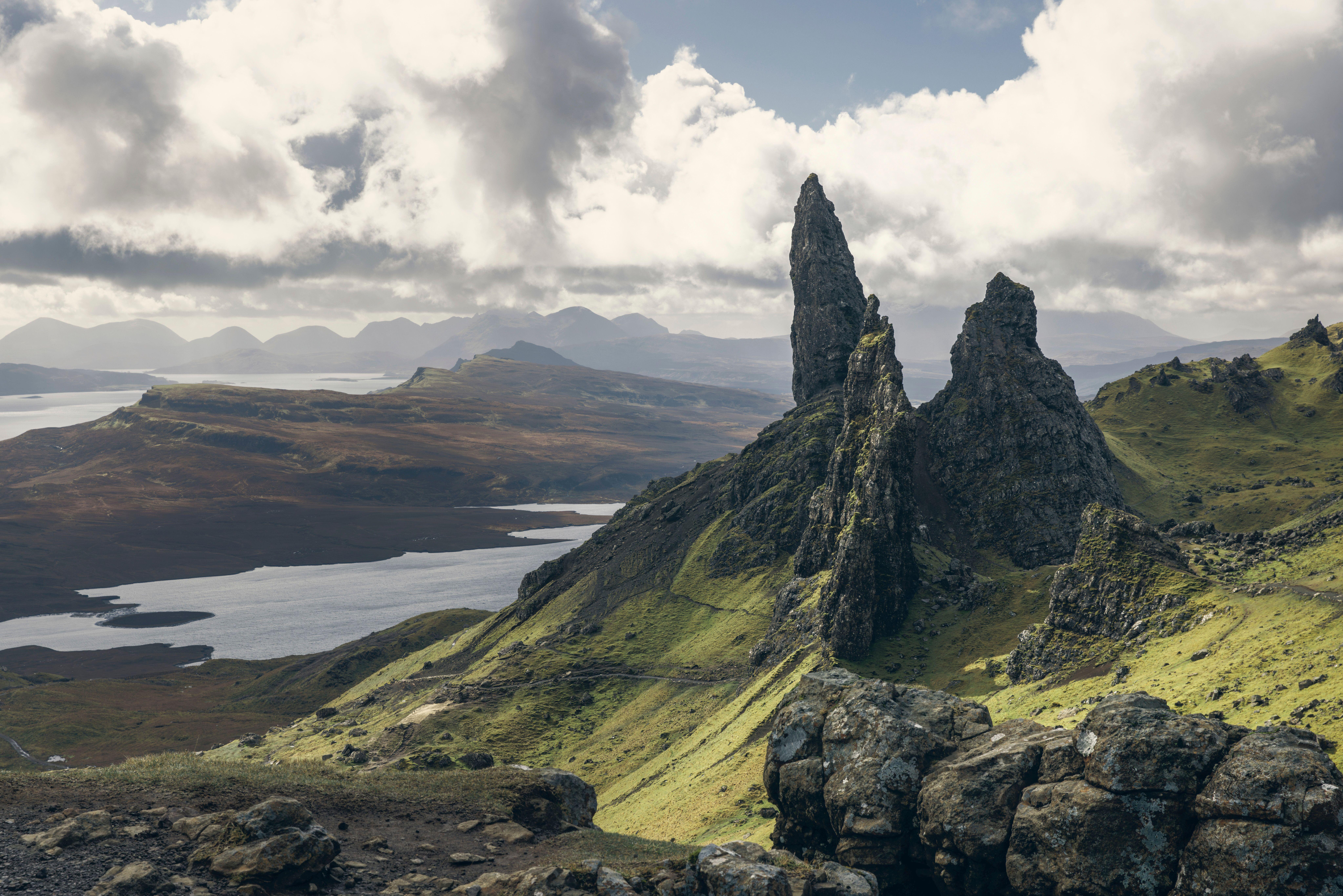 Jagged rocks at the top of a hill. In the background, rolling hills and bodies of water.