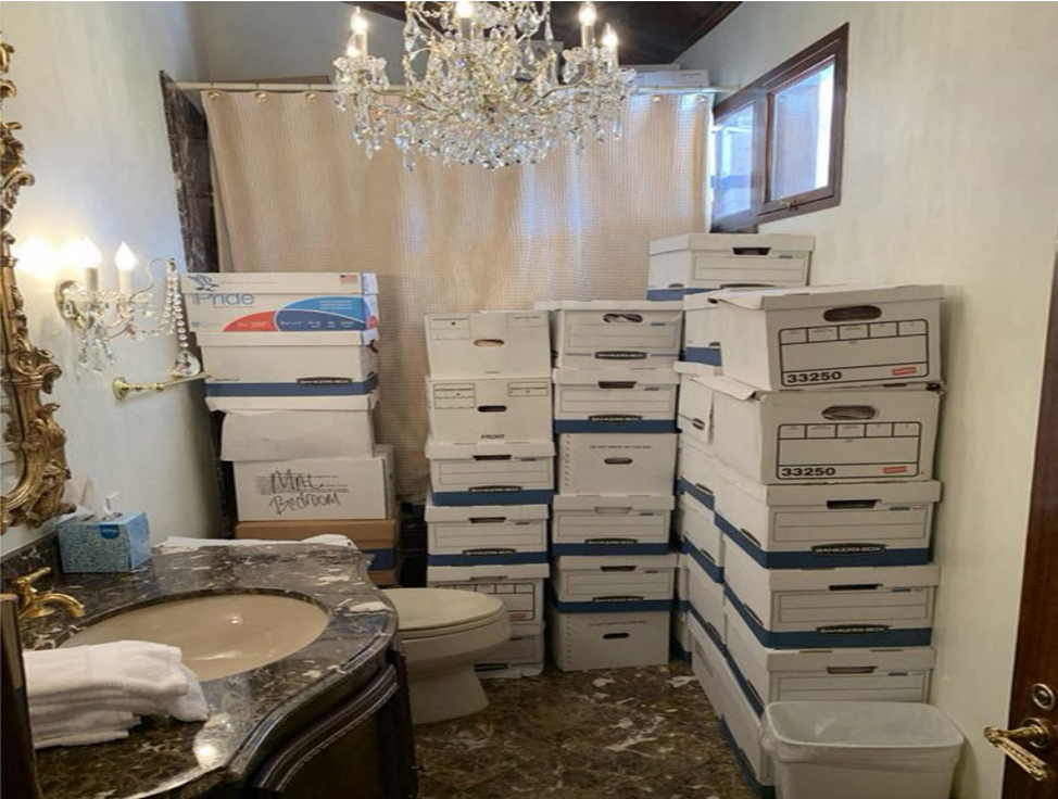 Stacks of boxes in a marble bathroom with a chandelier.