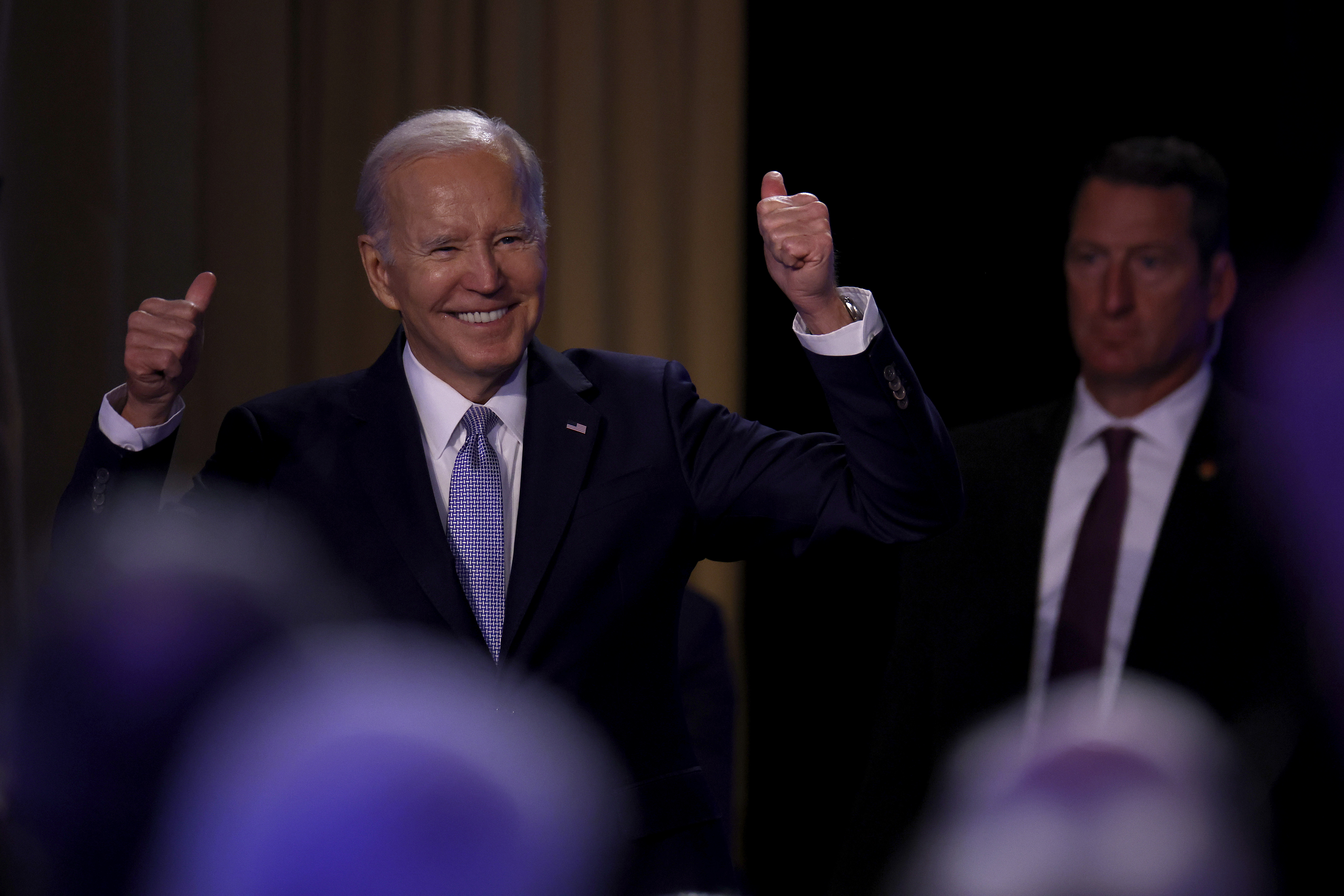 US President Joe Biden smiling with his hands in the air in celebration.