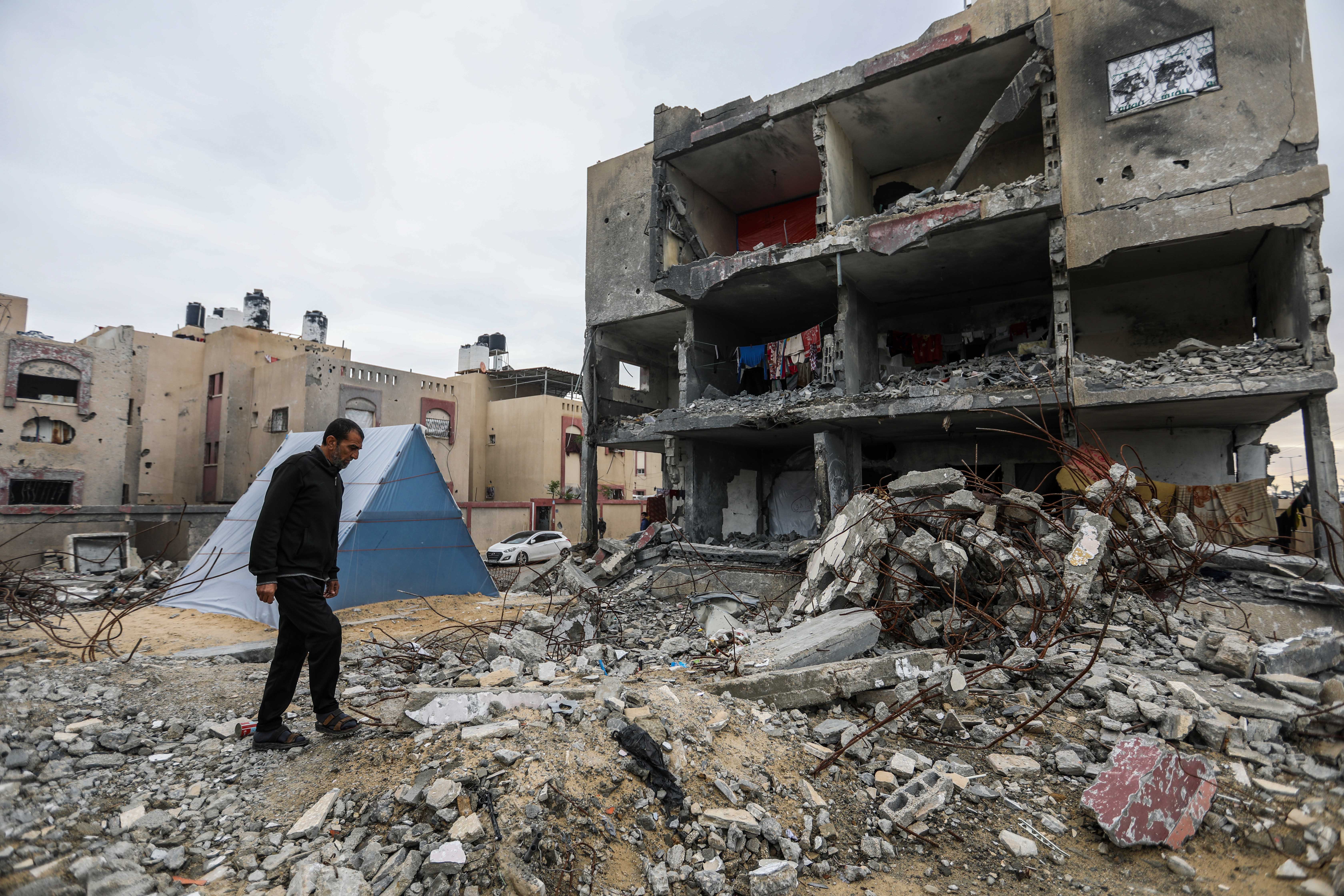 A man standing by the ruins of his home.