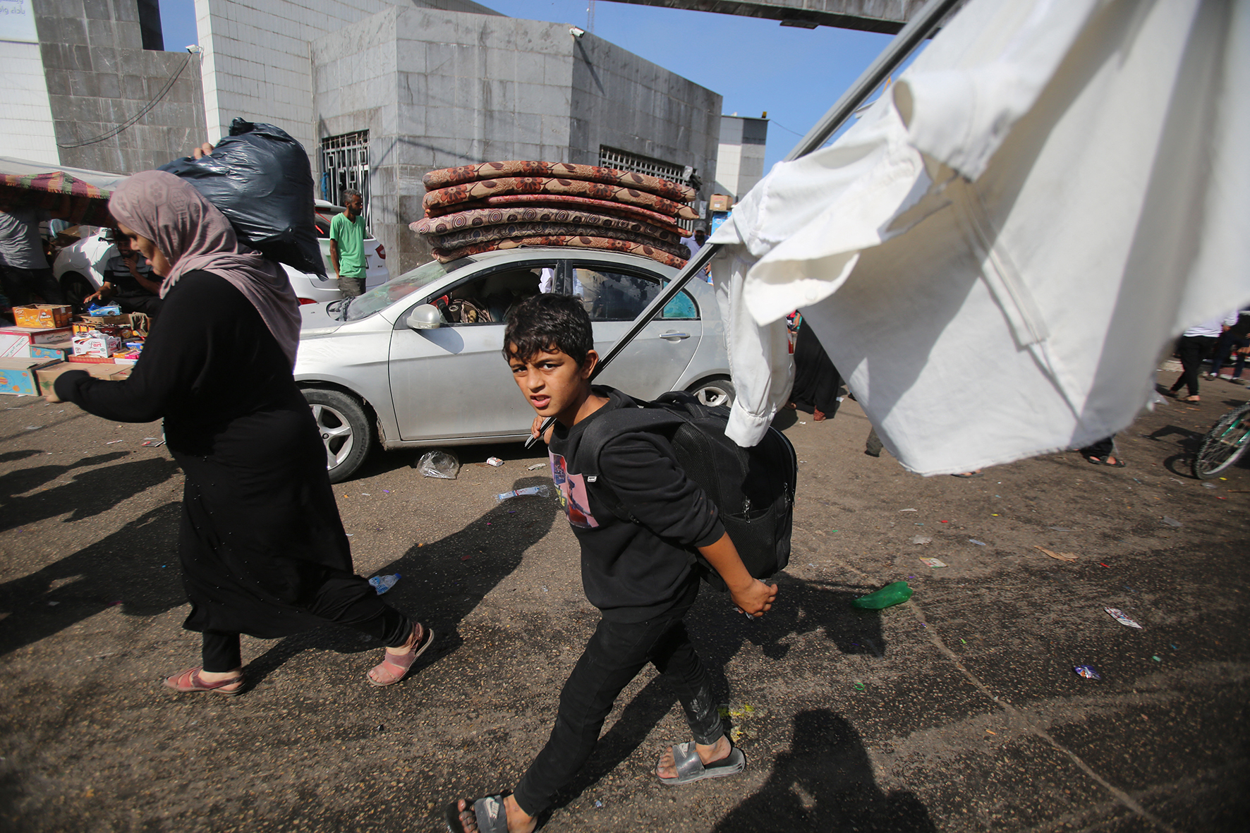 A Palestinian boy carries a makeshift white flag as he walks with his mother.