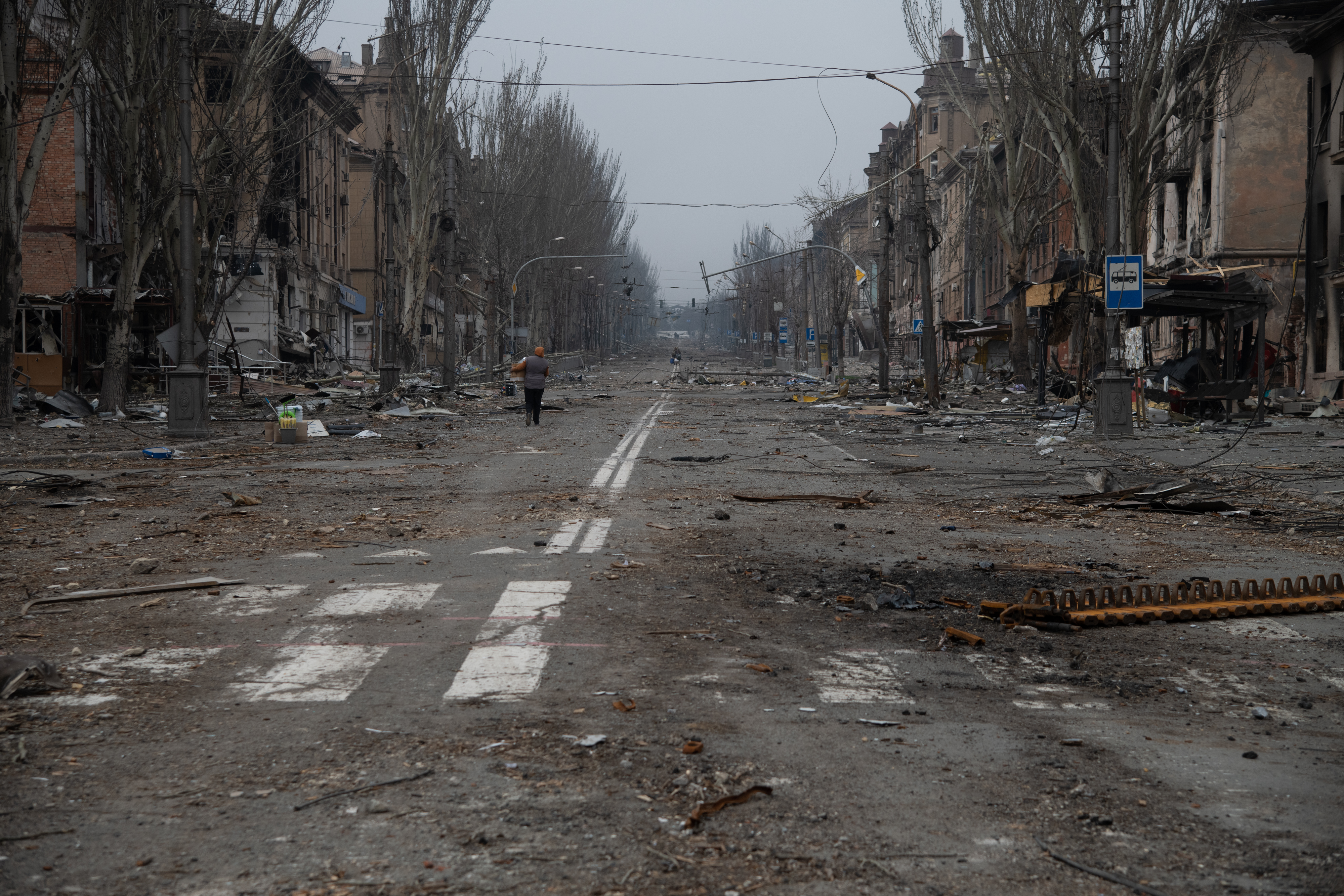 A woman walks down a street of bombed houses in Mariupol, Ukraine.