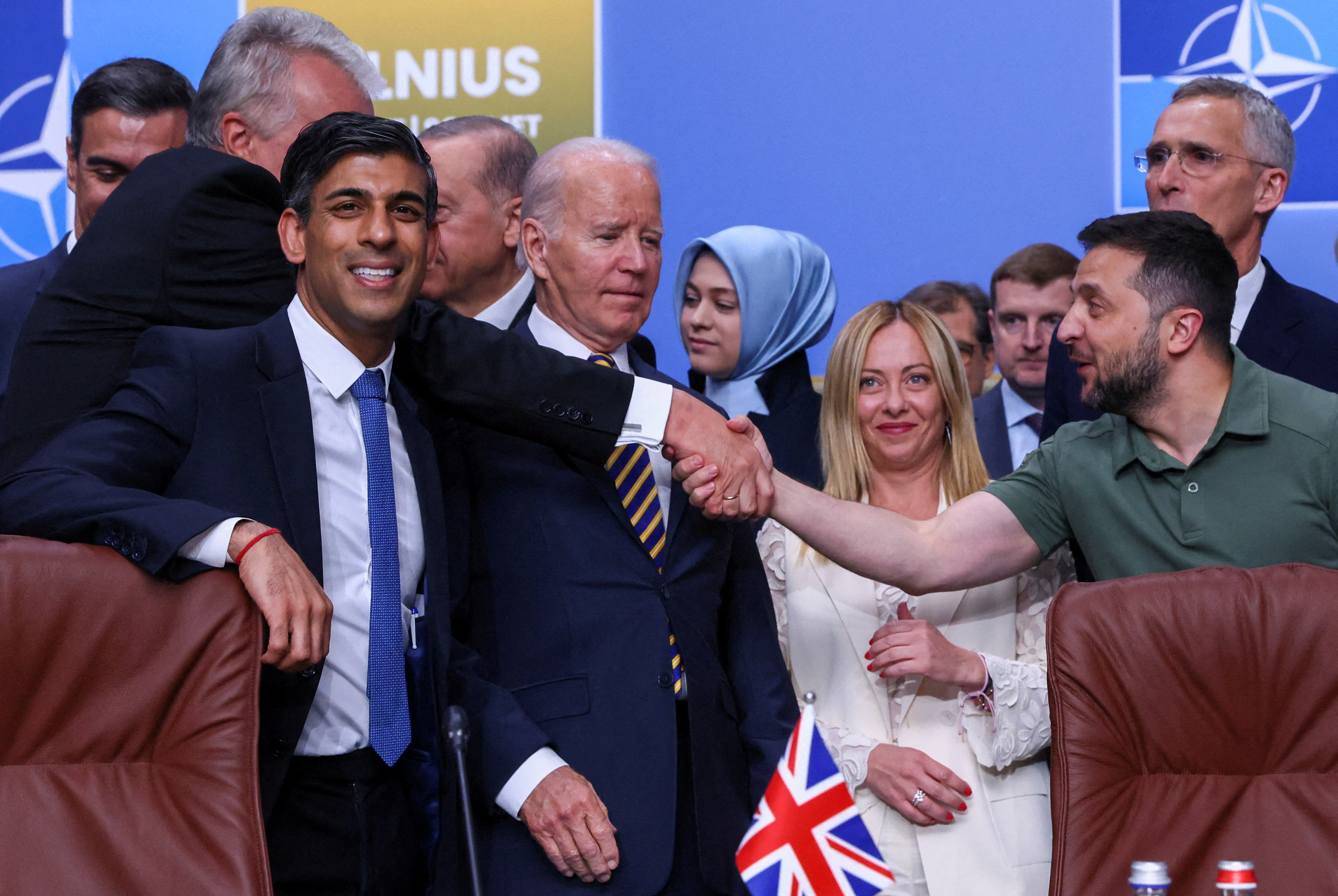 Politicians shake hands on stage.