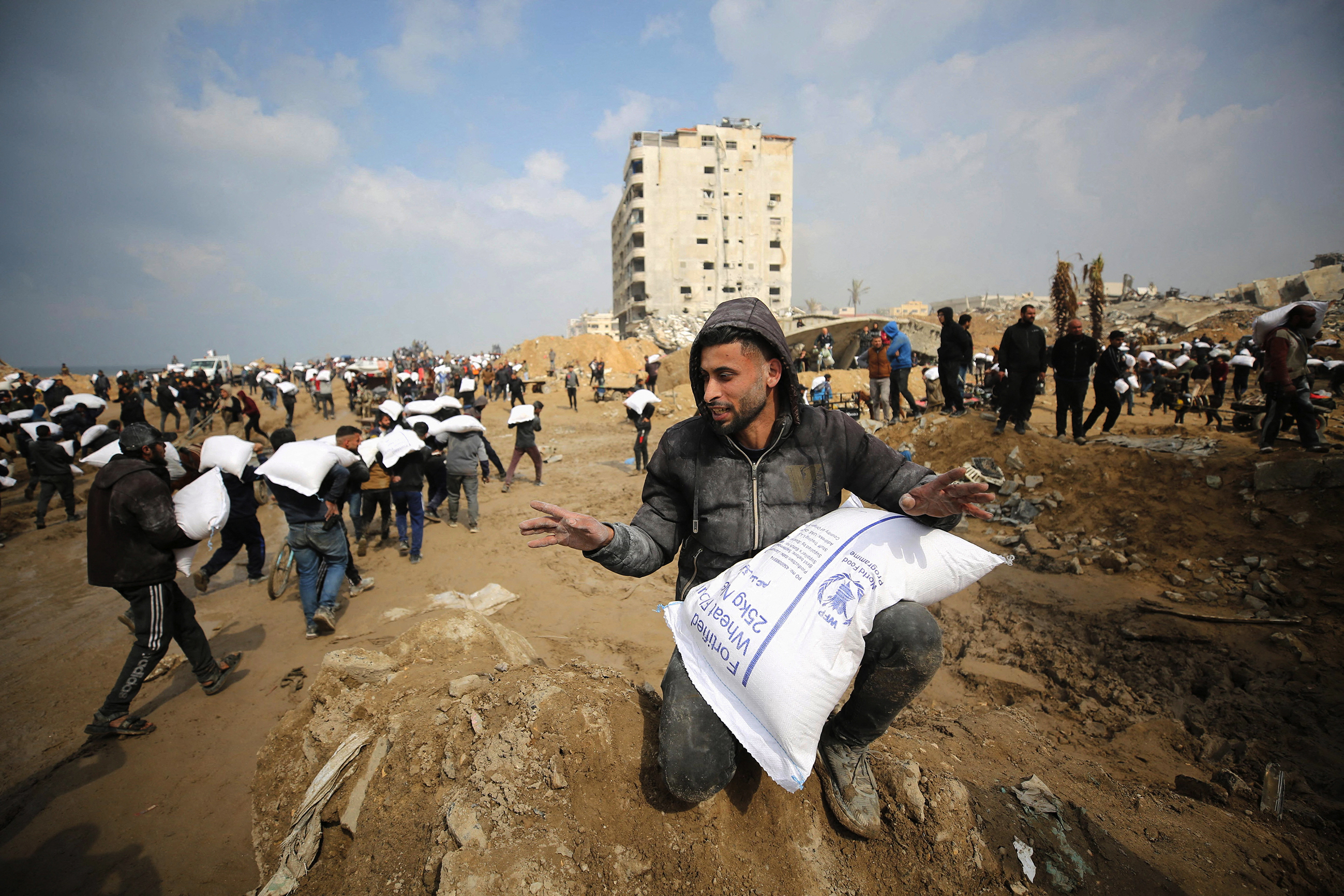 Palestinians carry bags of flour from an aid truck near an Israeli checkpoint in Gaza City. 