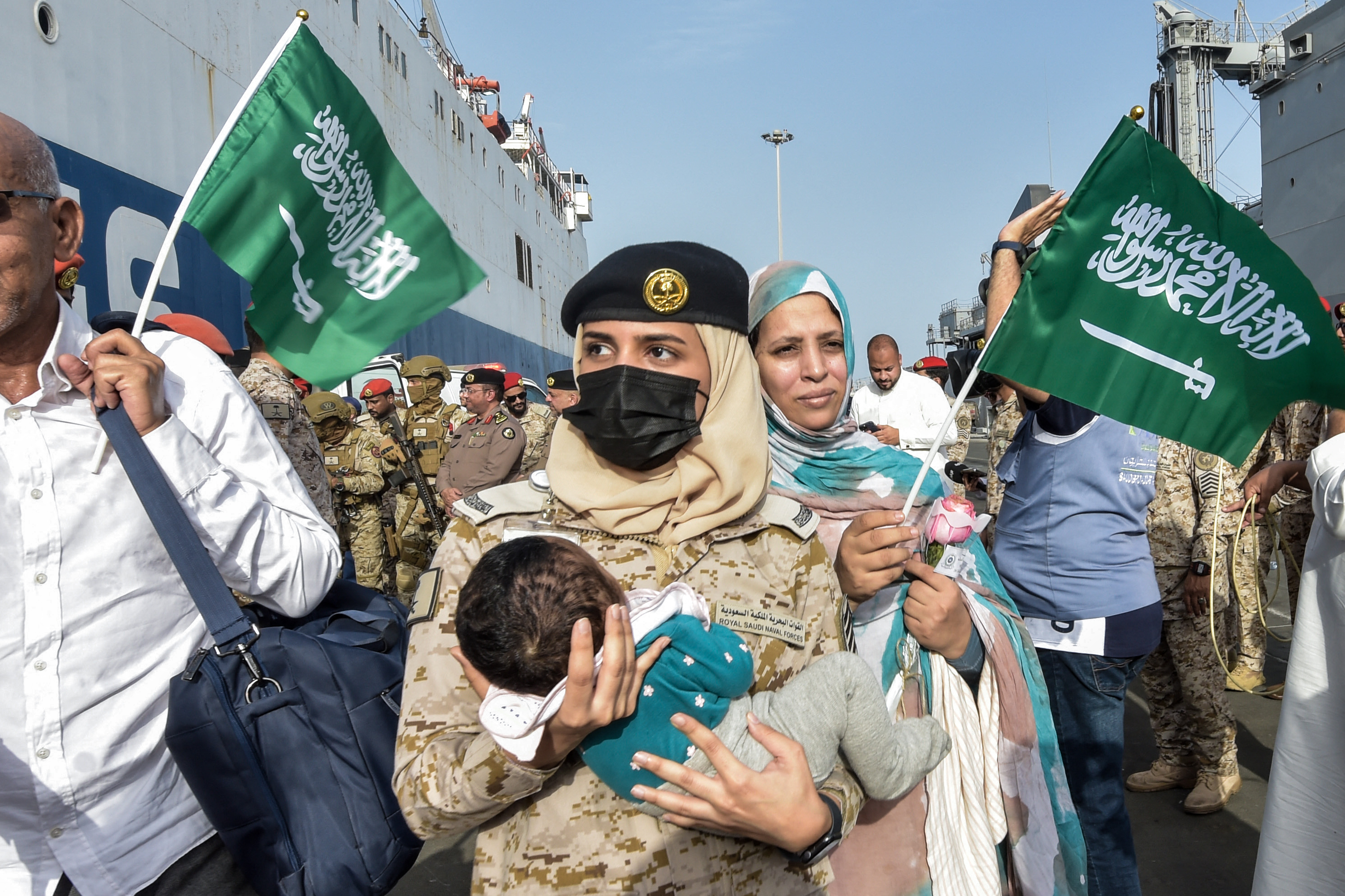 A Royal Saudi Naval Forces sailor carries a child as evacuees arrive at King Faisal Navy Base in Jeddah