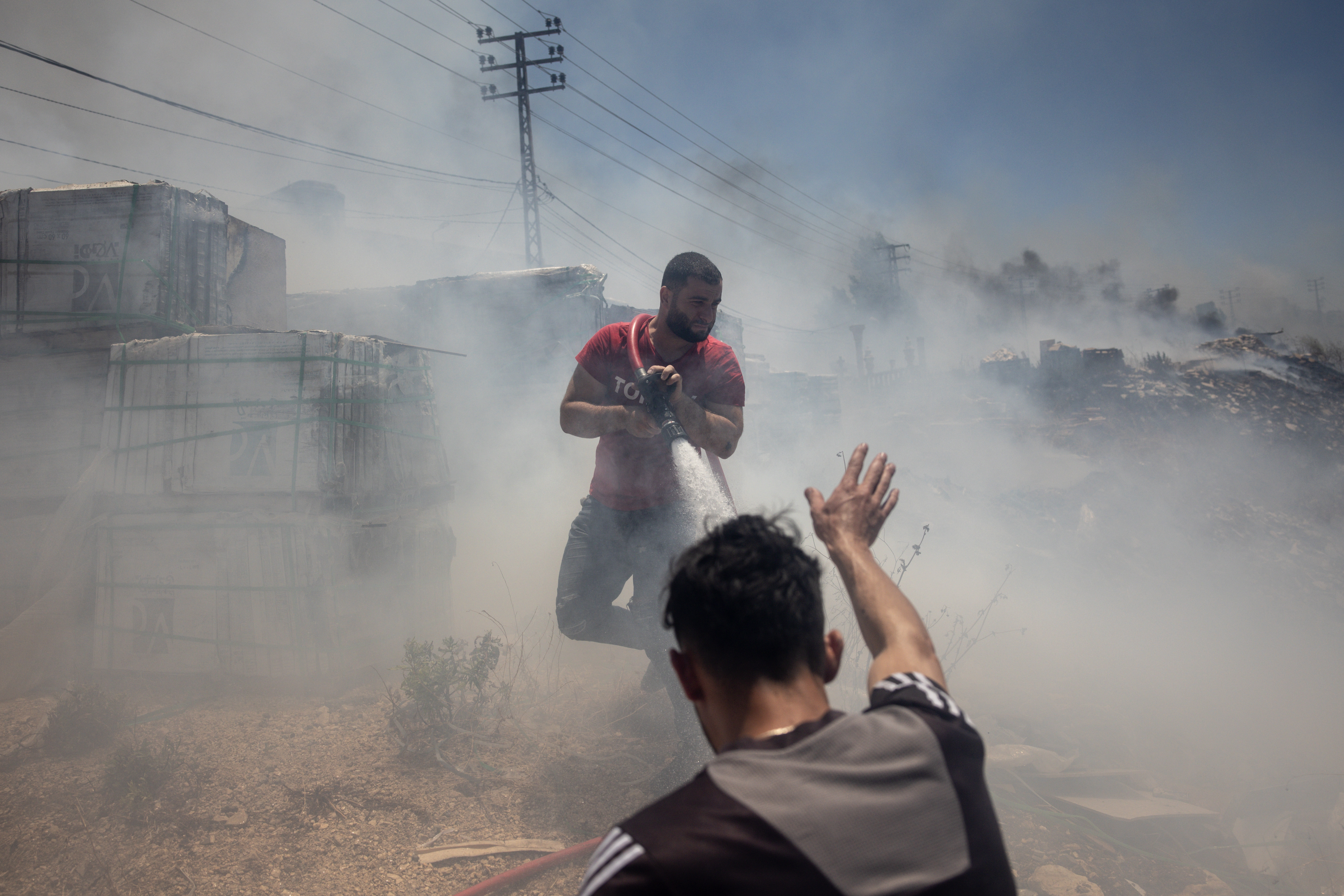 Civilians try to put out fires caused by Israeli missile strikes on targets in Bint Jbeil, Lebanon.