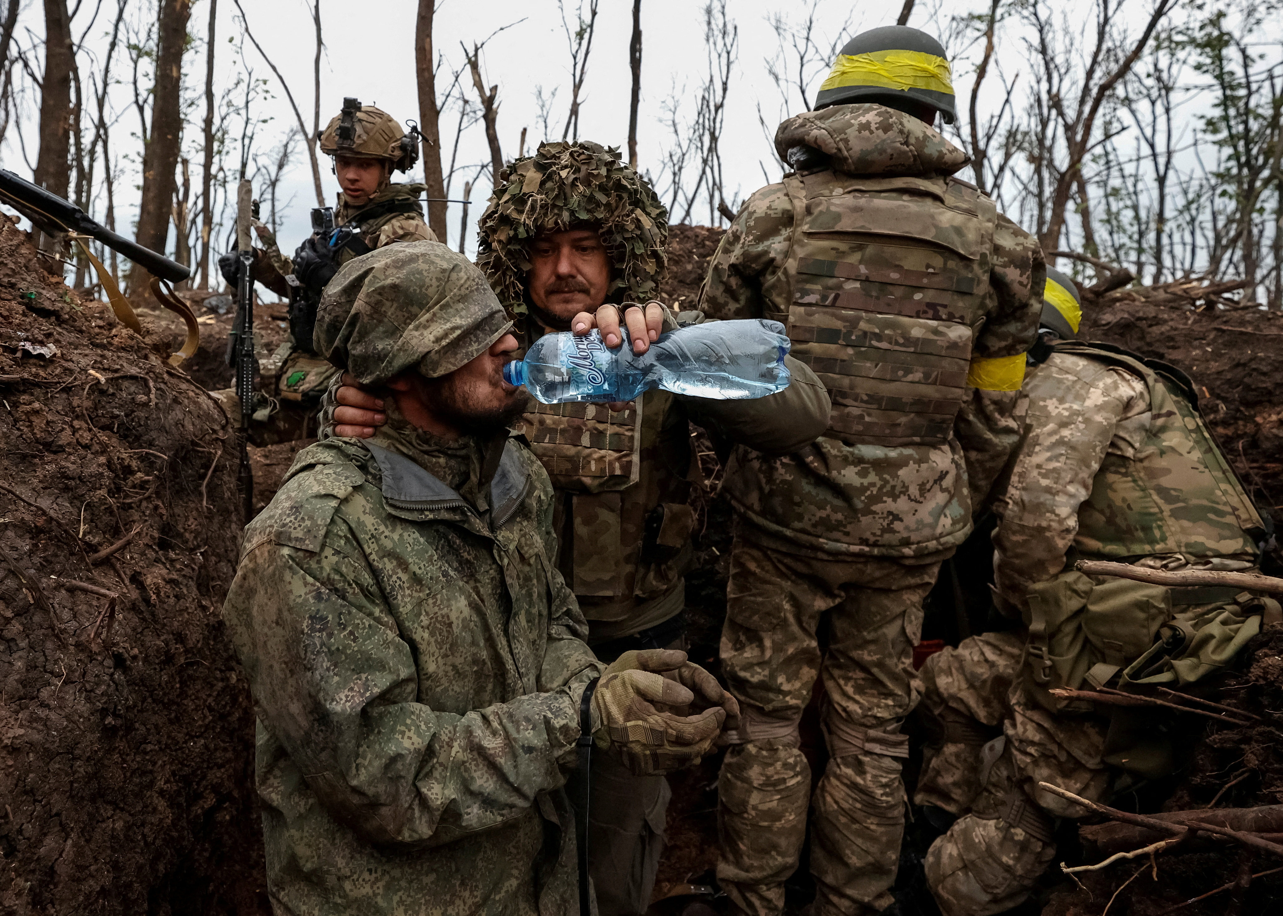 A Ukrainian soldier gives water to a captured Russian army serviceman, near the front-line city of Bakhmut in the Donetsk region.