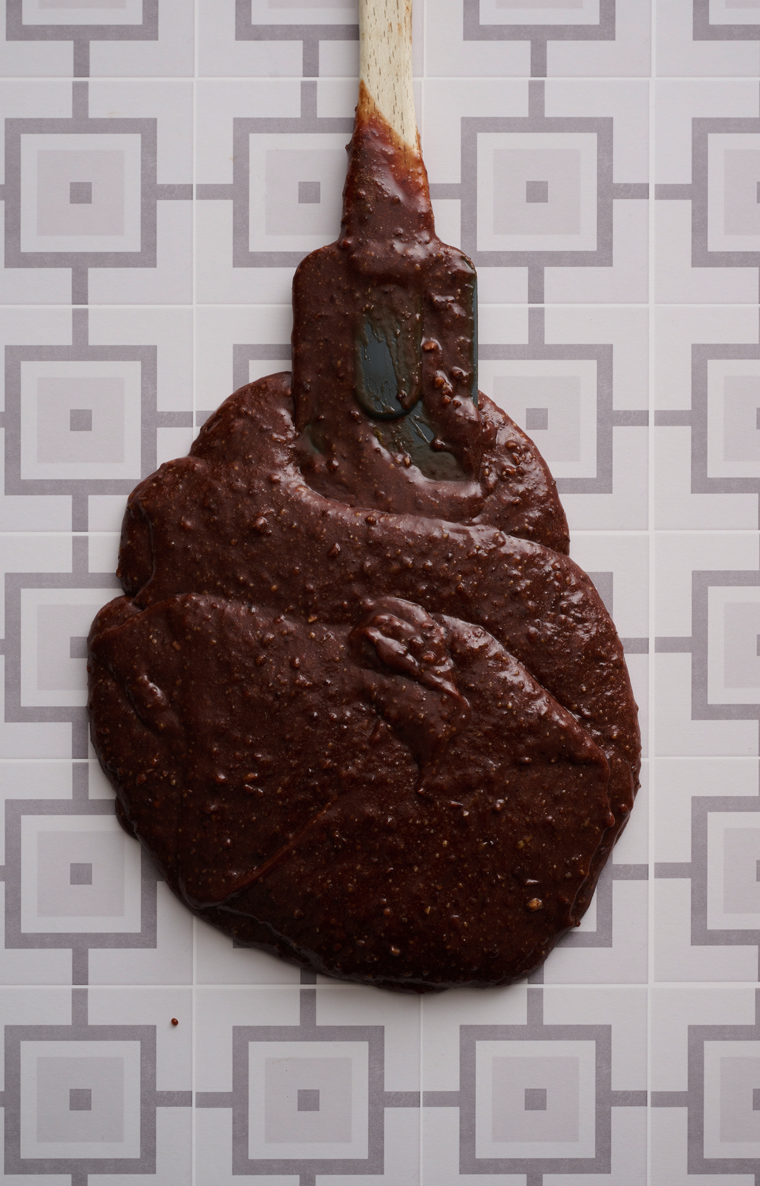 A spatula sits in a pool of chocolate cake drizzle batter