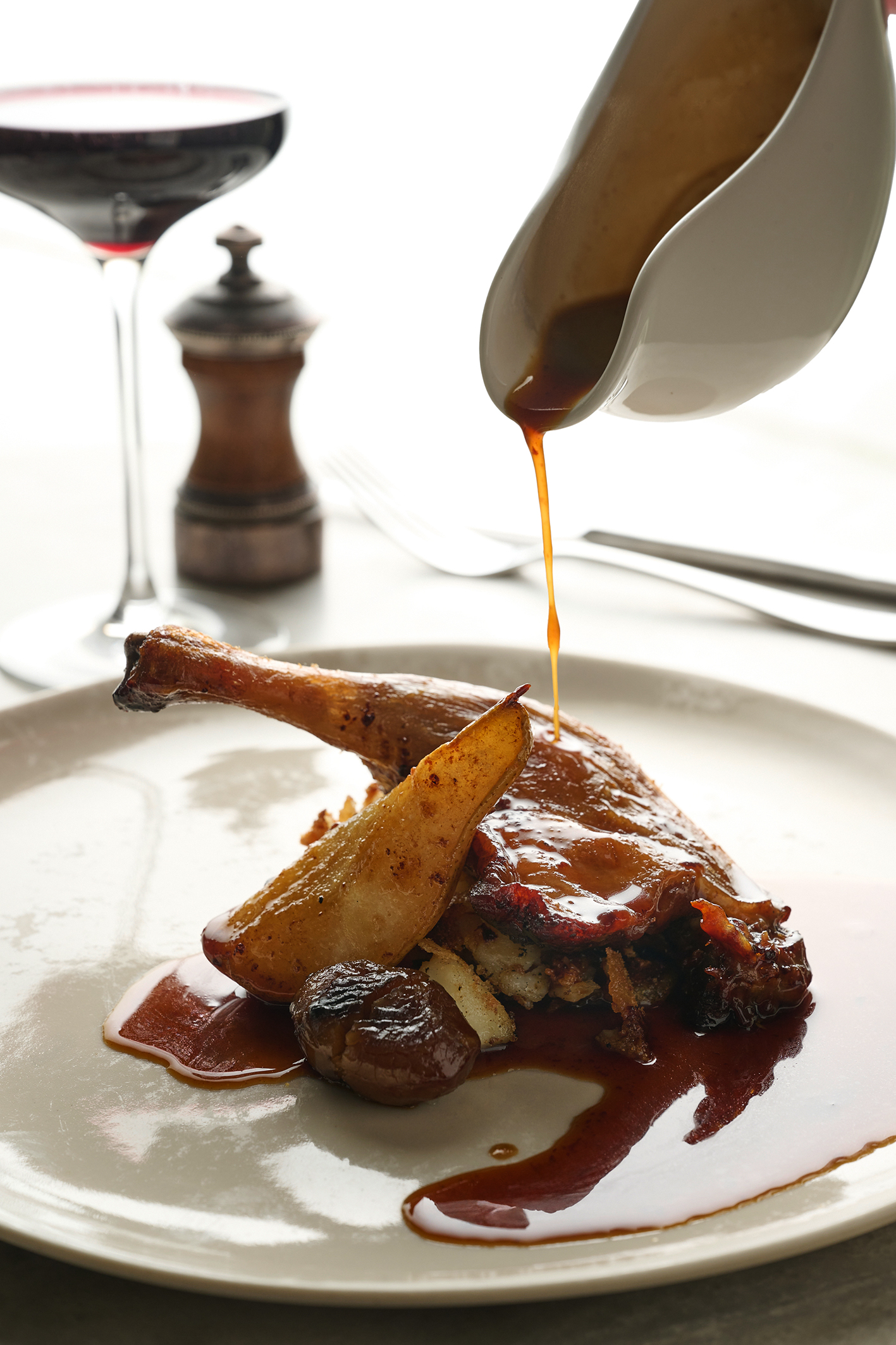 Crispy-skinned duck legs with chestnuts, baked pear and potatoes boulangère