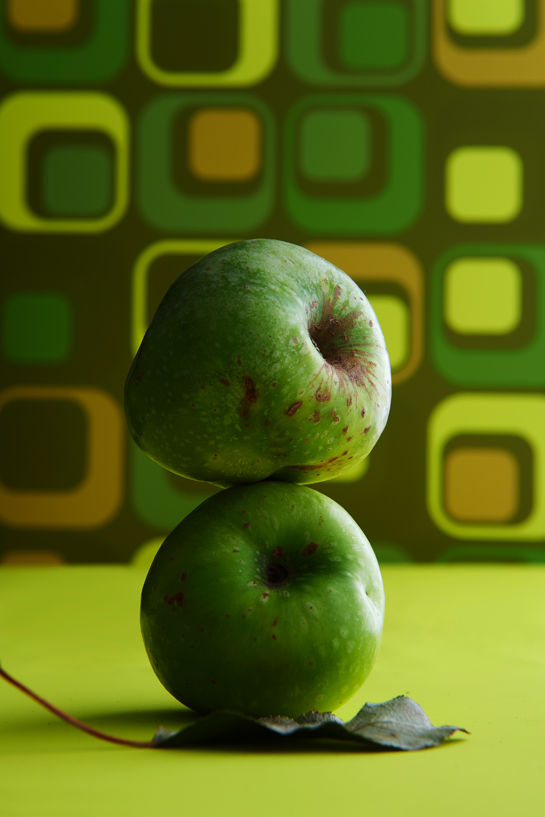 A green apple stacked on top of another.