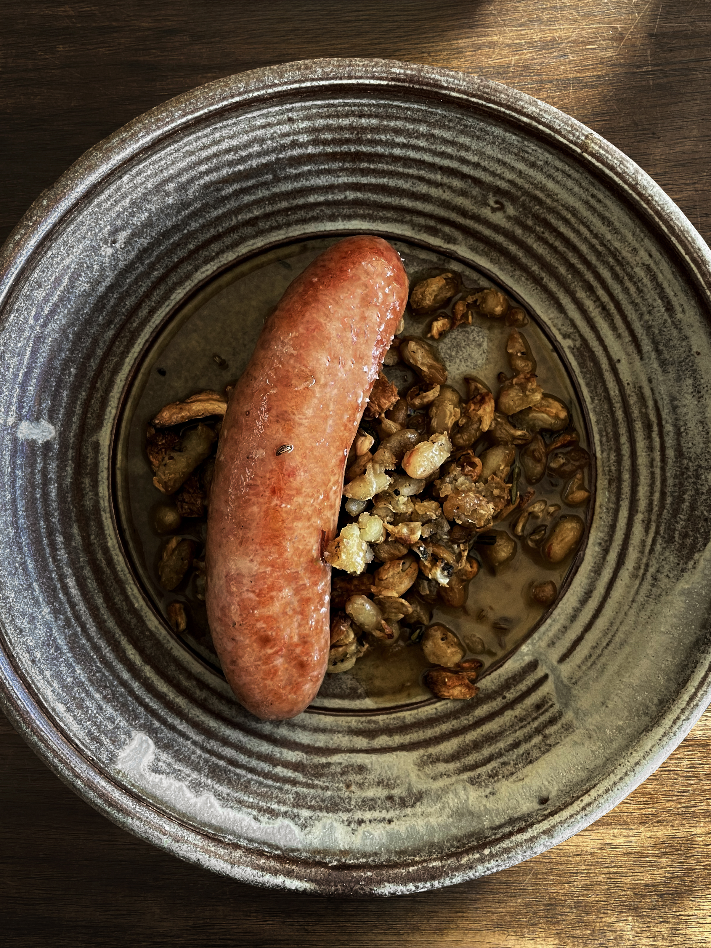 A sausage and beans in a pot.