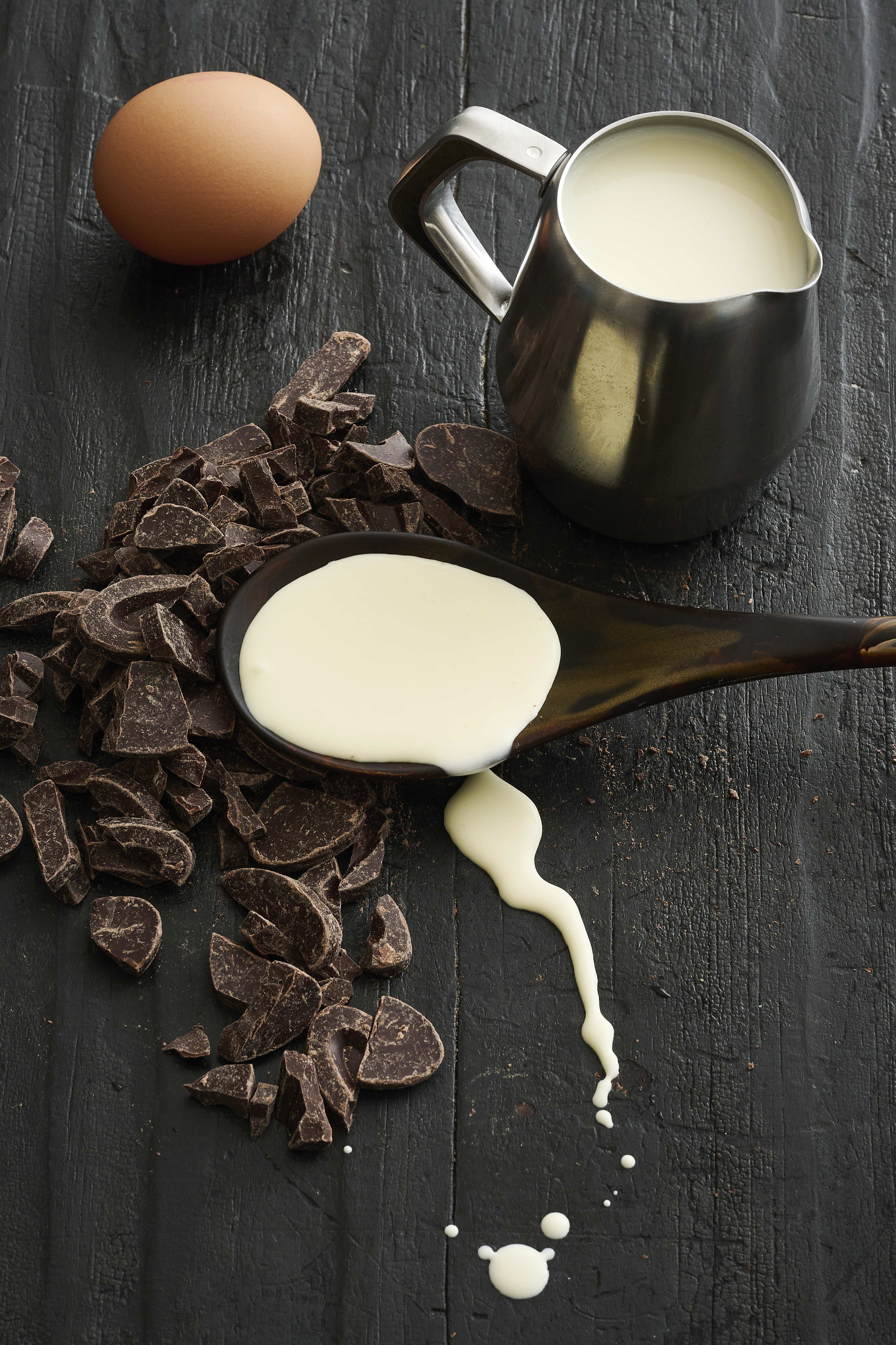 Pieces of chocolate, an egg and a jug of pouring cream.