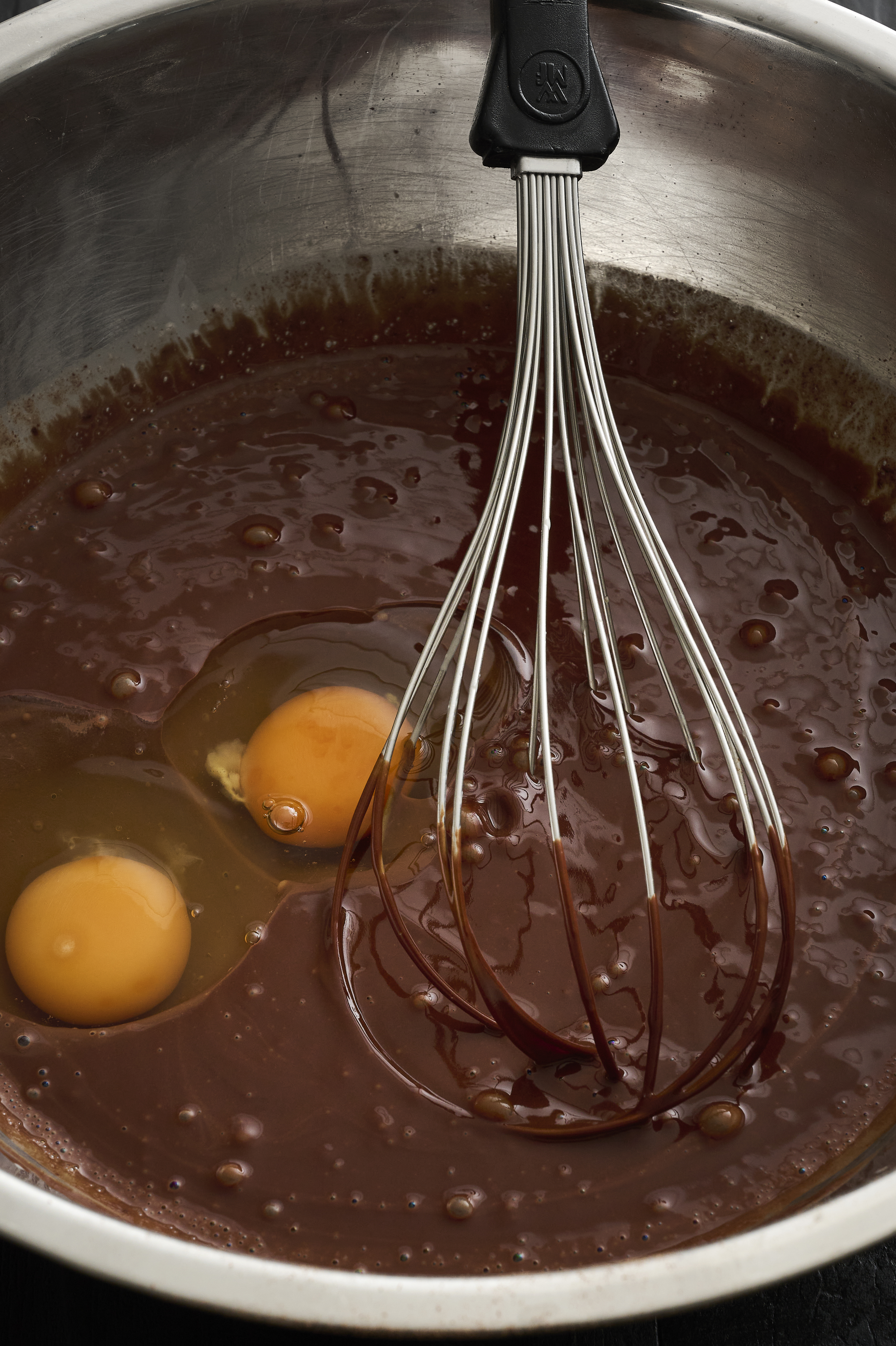 Chocolate mix with two raw eggs in a silver bowl.