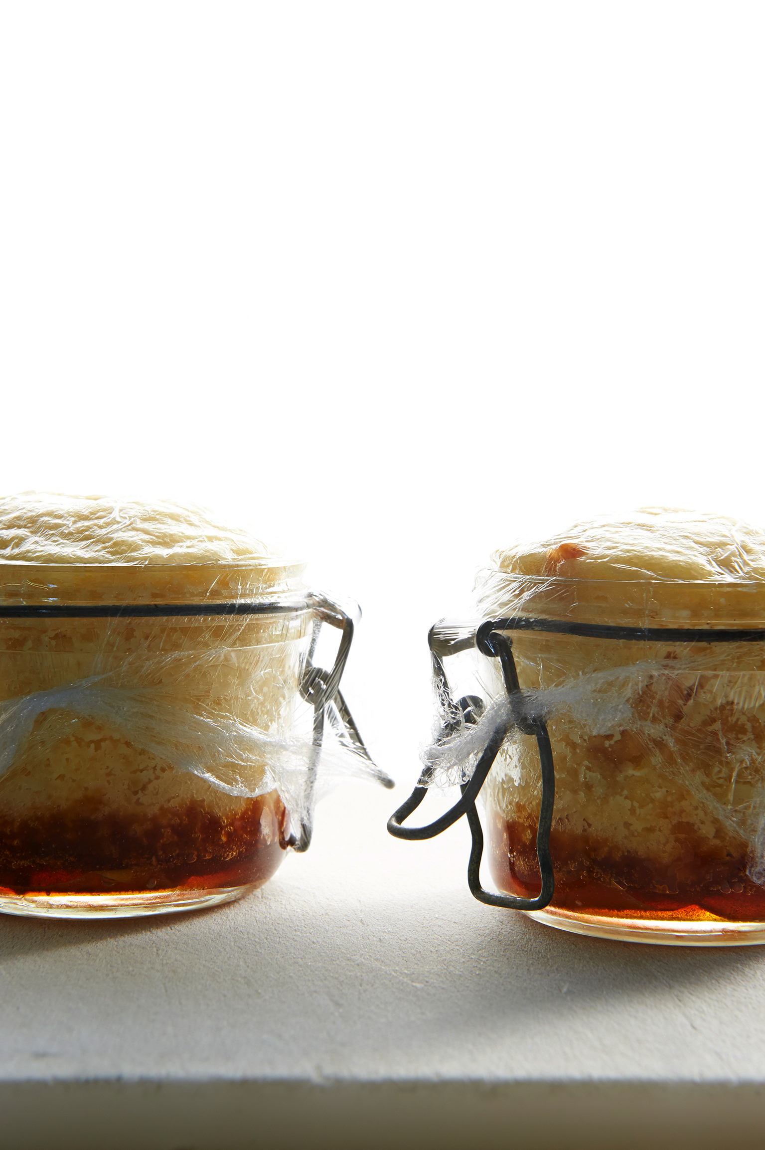 Ginger pudding in jars with plastic wrapping over them.