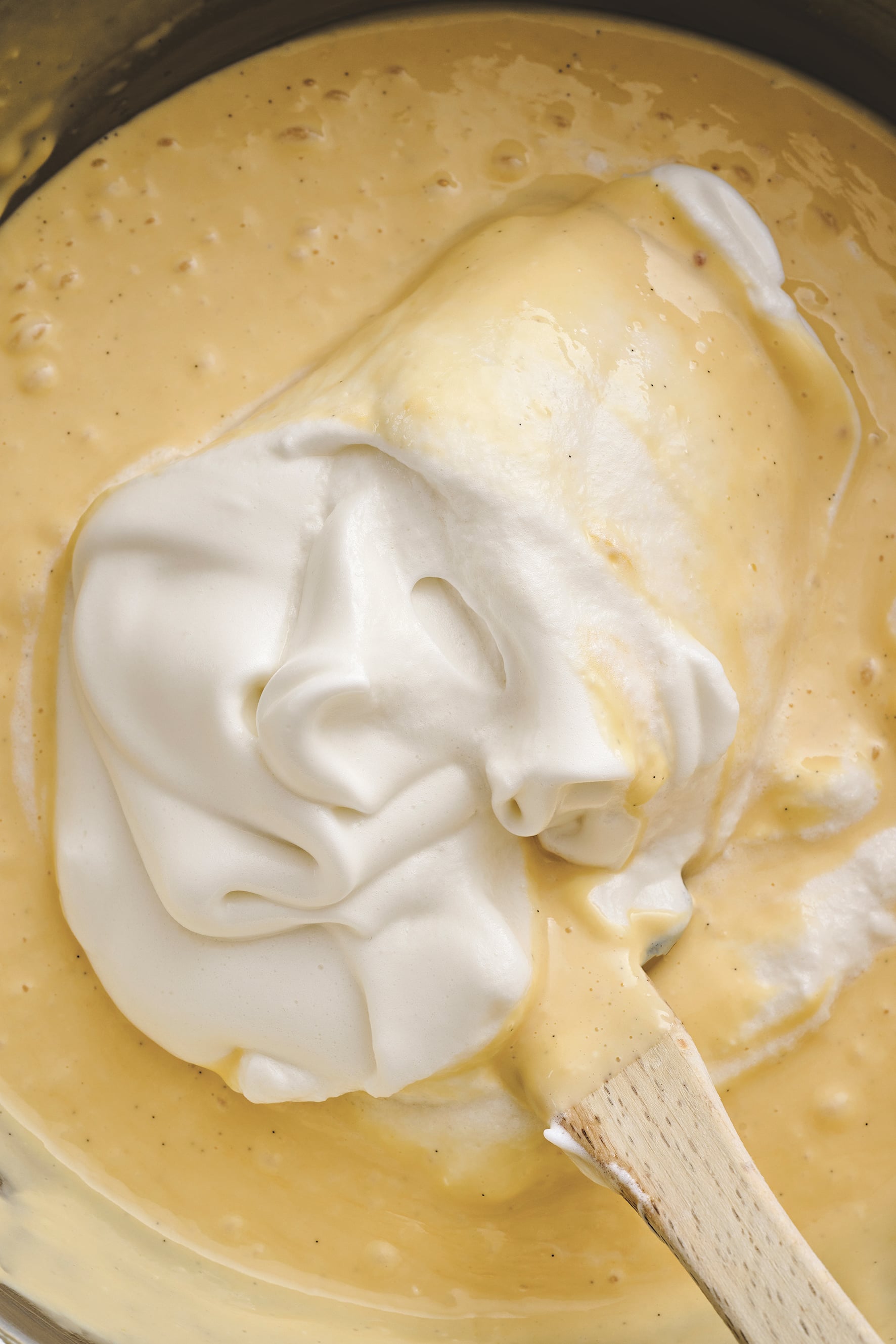 Cream is folded into a bowl of cheesecake batter