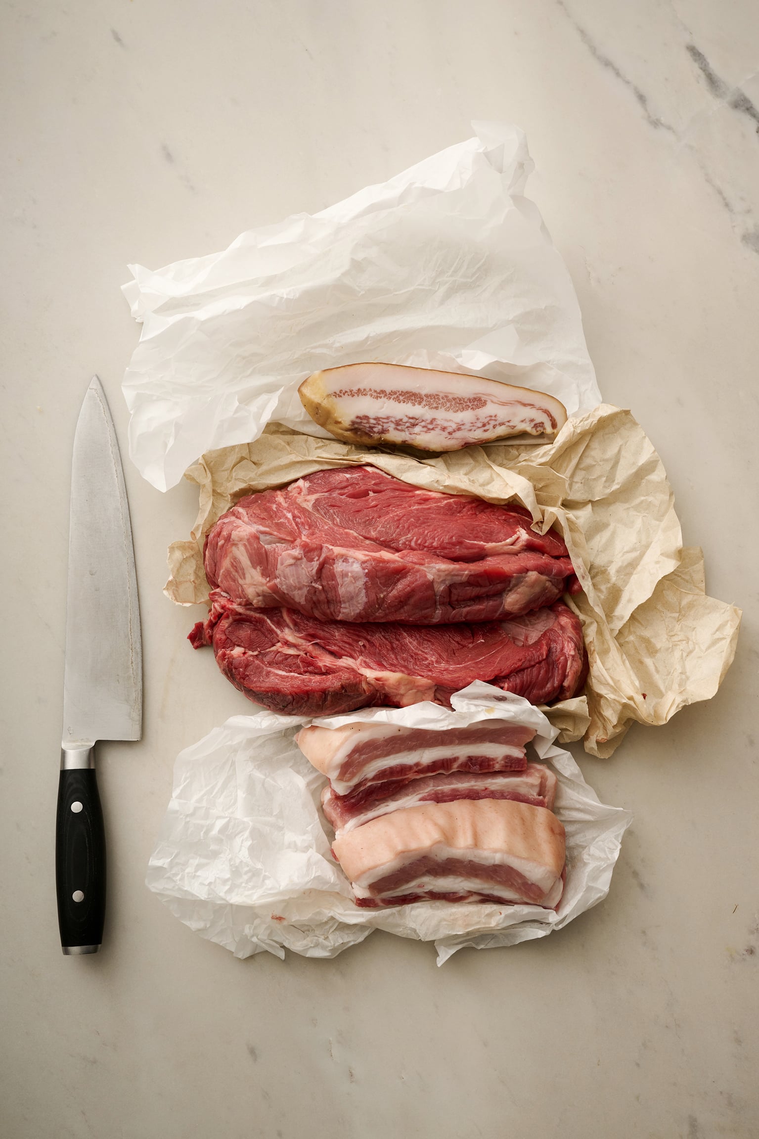 Beef steaks half wrapped in paper.