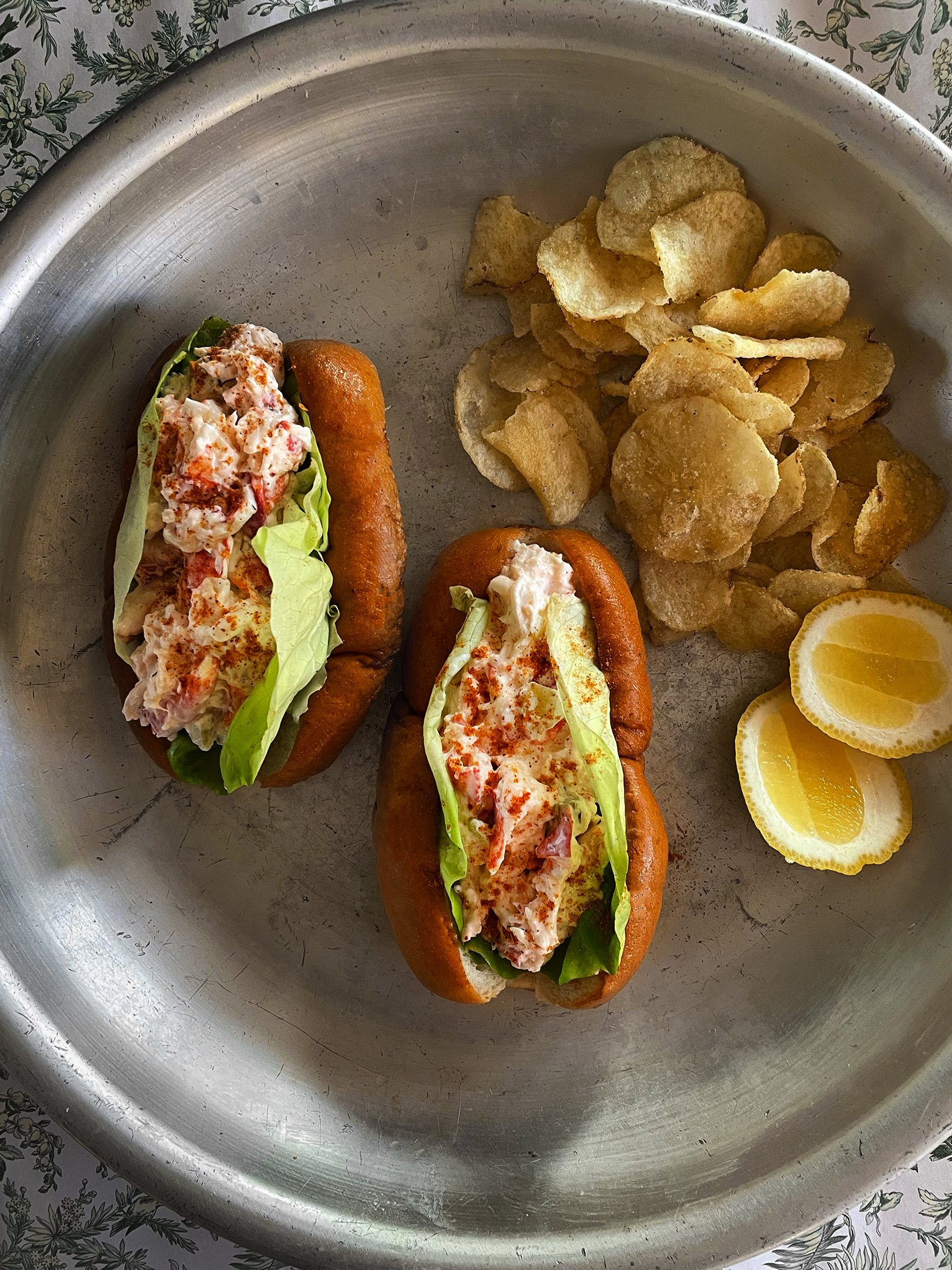 Lobster rolls served with lemon and potato chips.