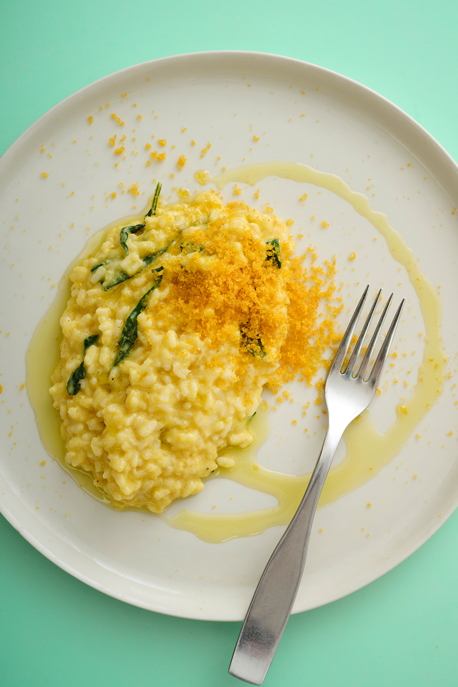 Corn risotto served with a fork on a white plate.