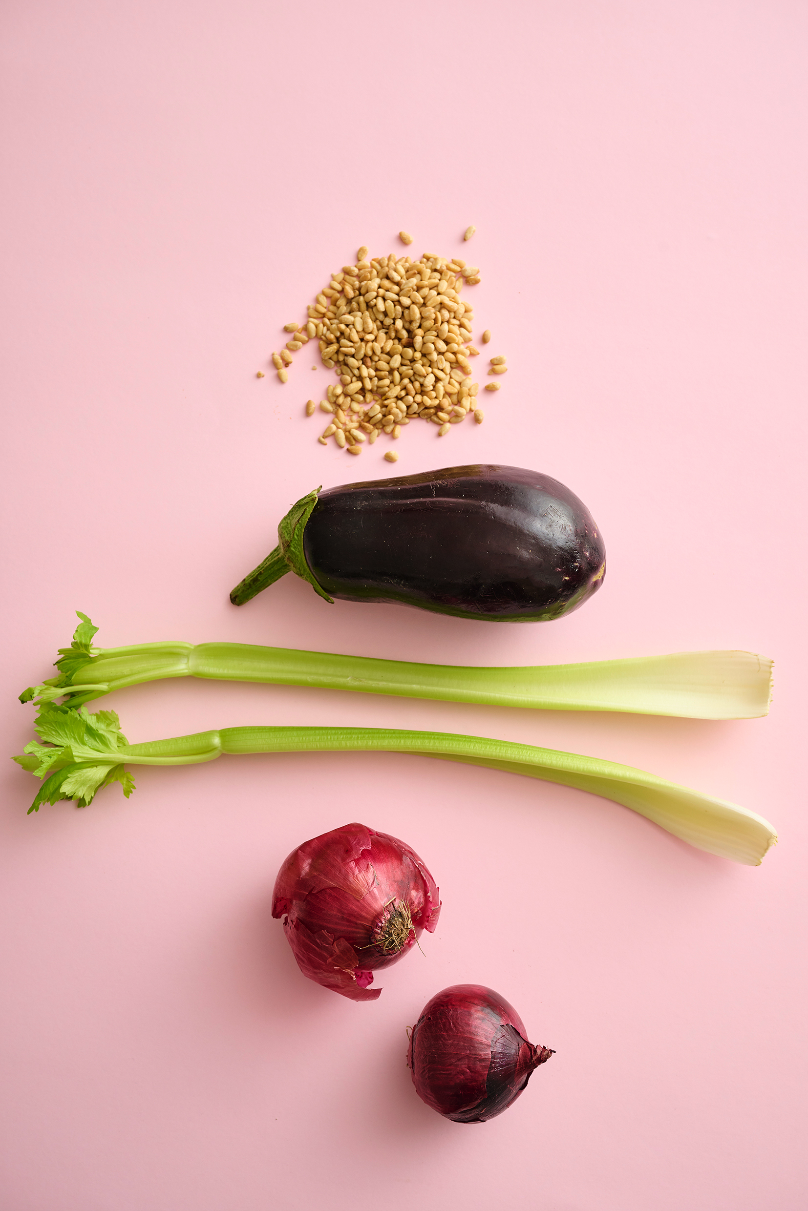 Two red onions, eggplant, pine nuts and celery stalks