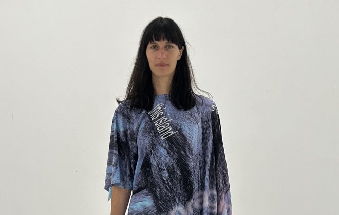 A model with dark brown hair wears a blue, loose-hanging outfit.